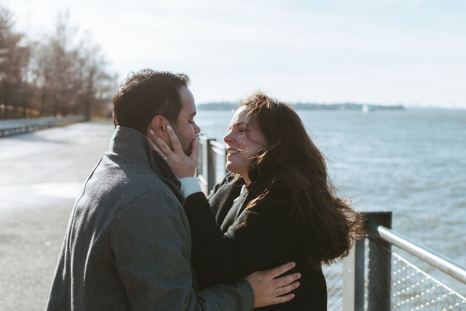 Recently engaged couple in DUMBO, Brooklyn kissing by the East River