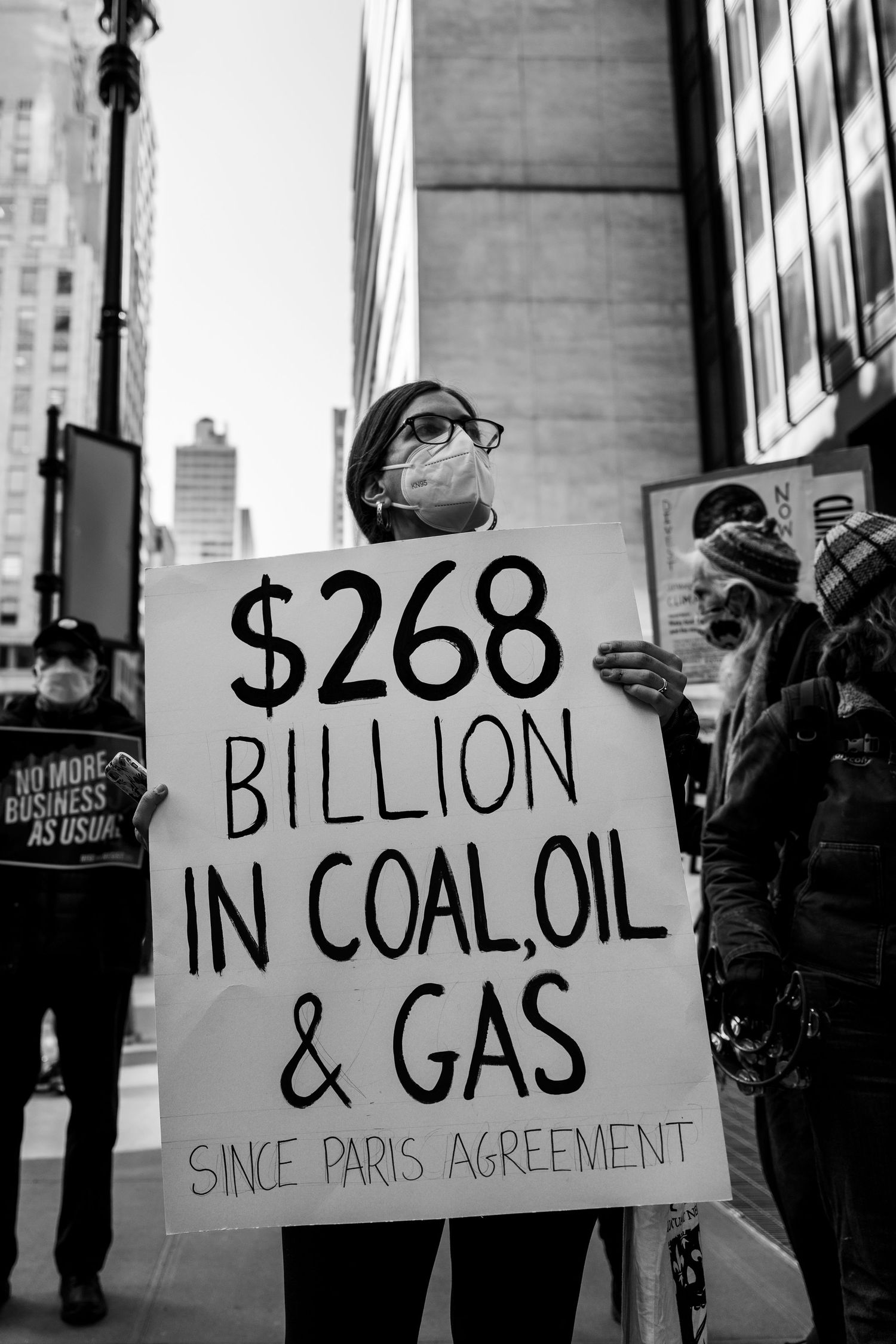 Masked woman holding a sign protesting fossil fuels