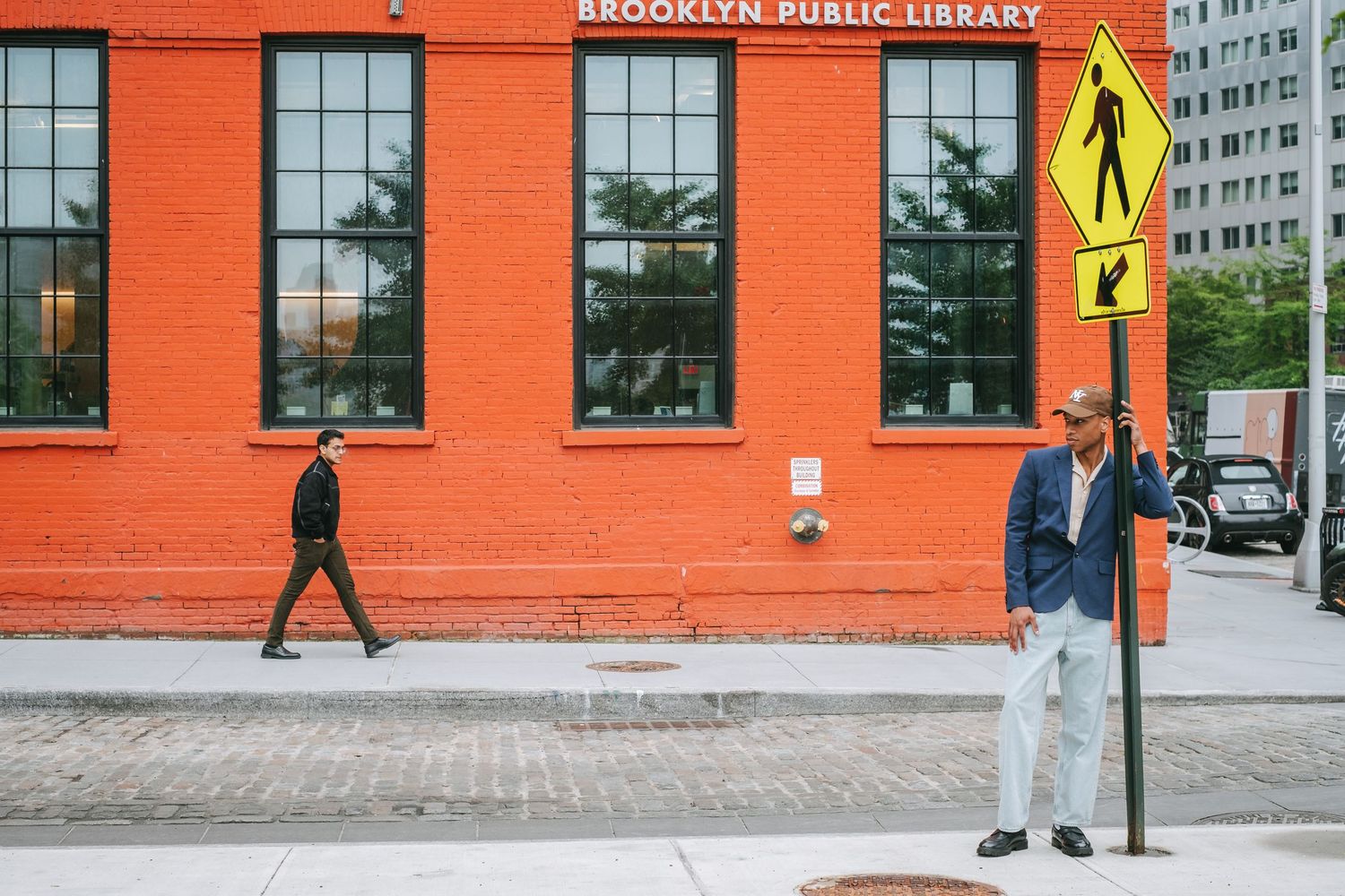 A man leaning against a street sign in Brooklyn