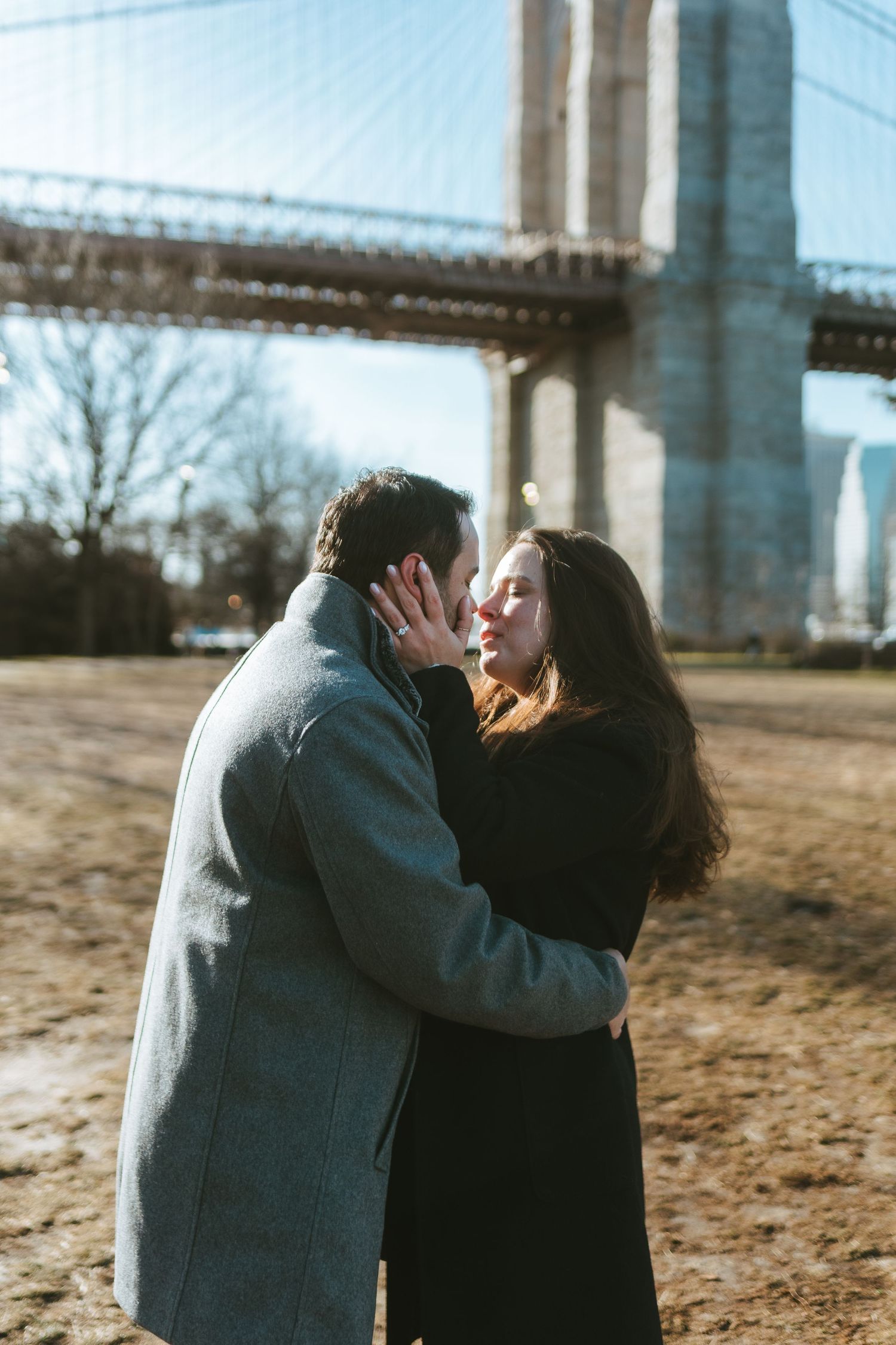 Recently engaged couple in DUMBO, Brooklyn standing near the Brooklyn Bridge