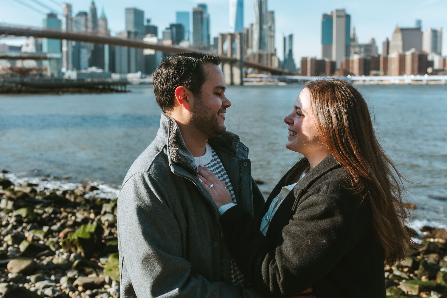 Recently engaged couple in DUMBO, Brooklyn standing on Pebble Beach