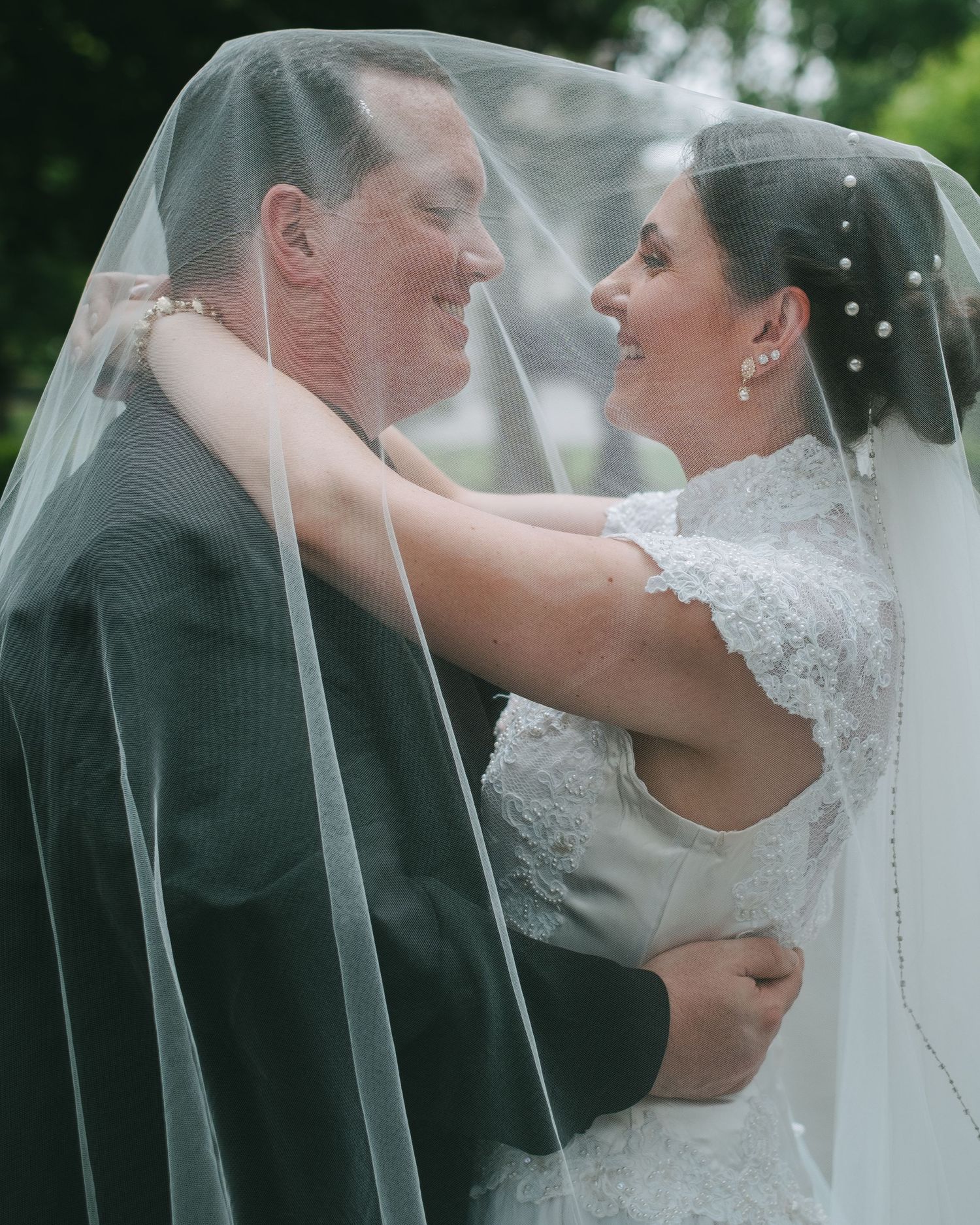 A married couple embracing under a sheer veil