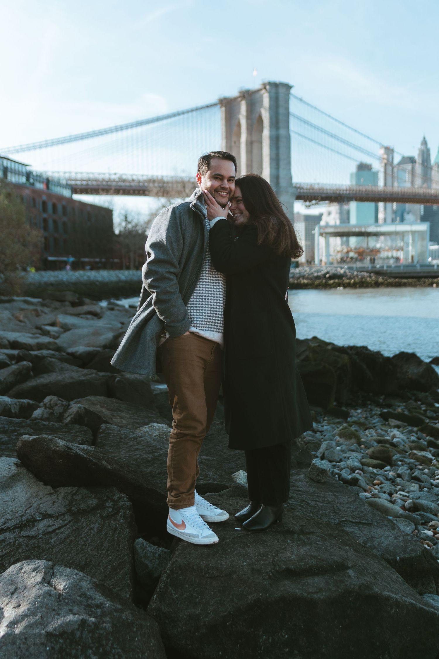 Recently engaged couple in DUMBO, Brooklyn standing on Pebble Beach