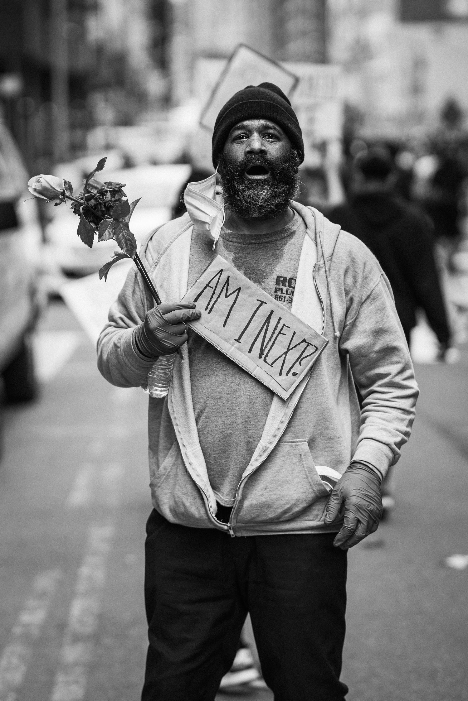 Black man holding a flower and a sign in protest of police brutality