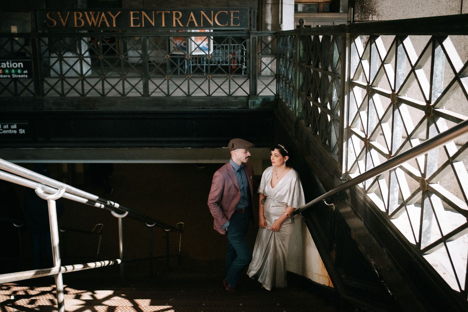 A recently married man and woman standing on the stairs of a subway entrance in New York City