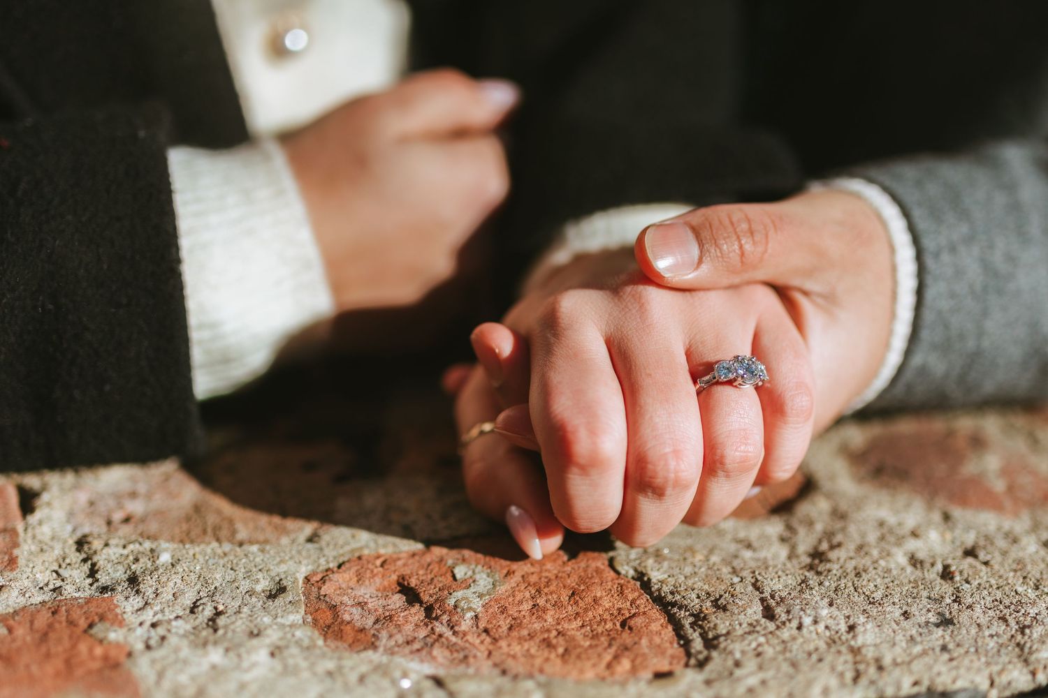 Recently engaged couple in DUMBO, Brooklyn holding hands and showing her ring