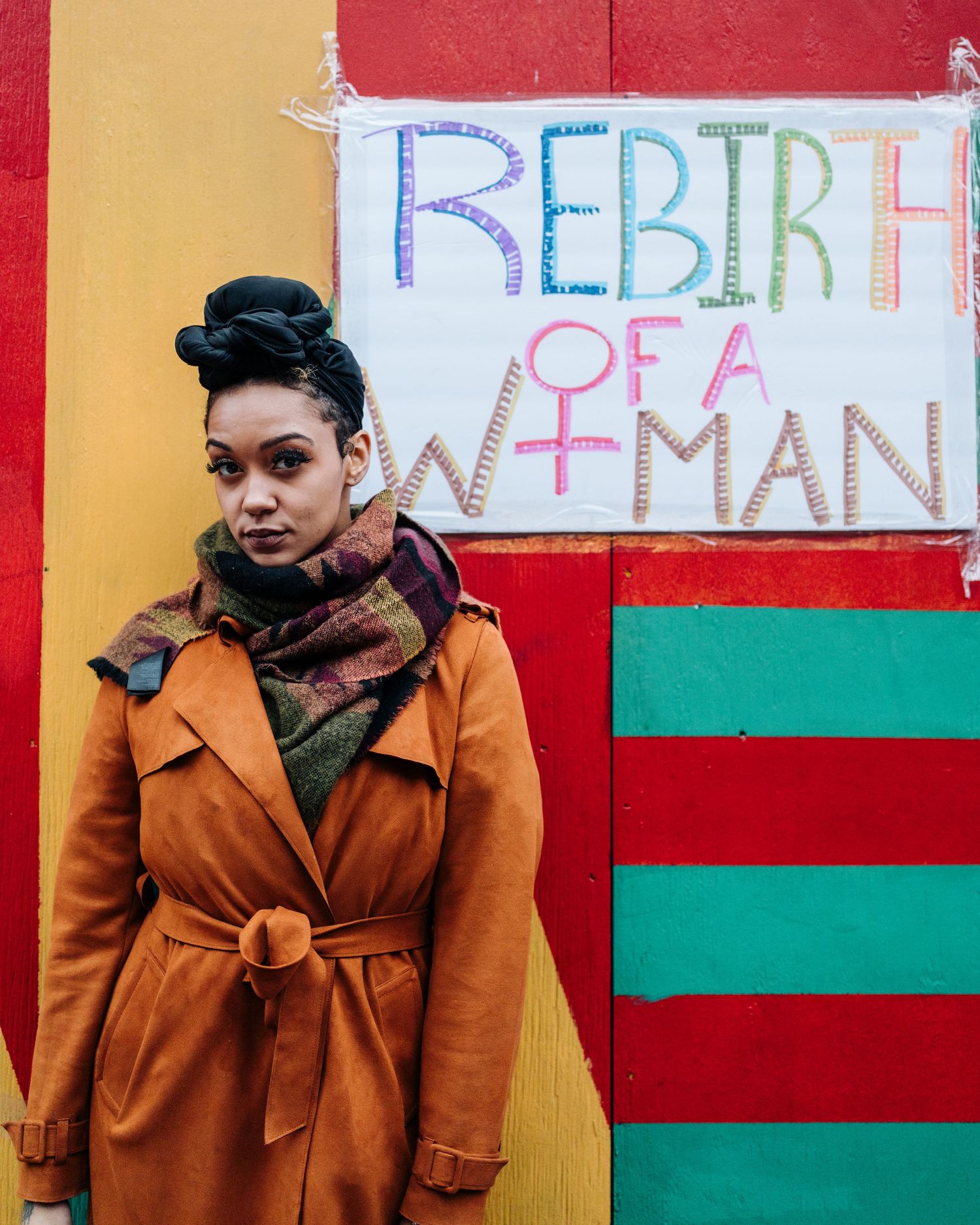 A black woman standing next to a color sign that reads 