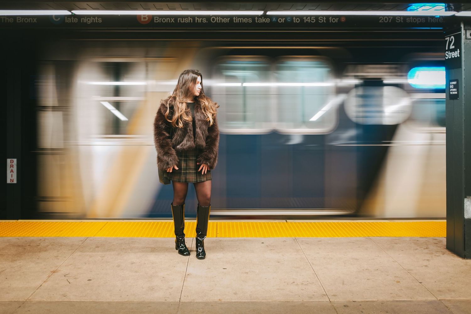 Woman posing alongside a moving subway train in New York City
