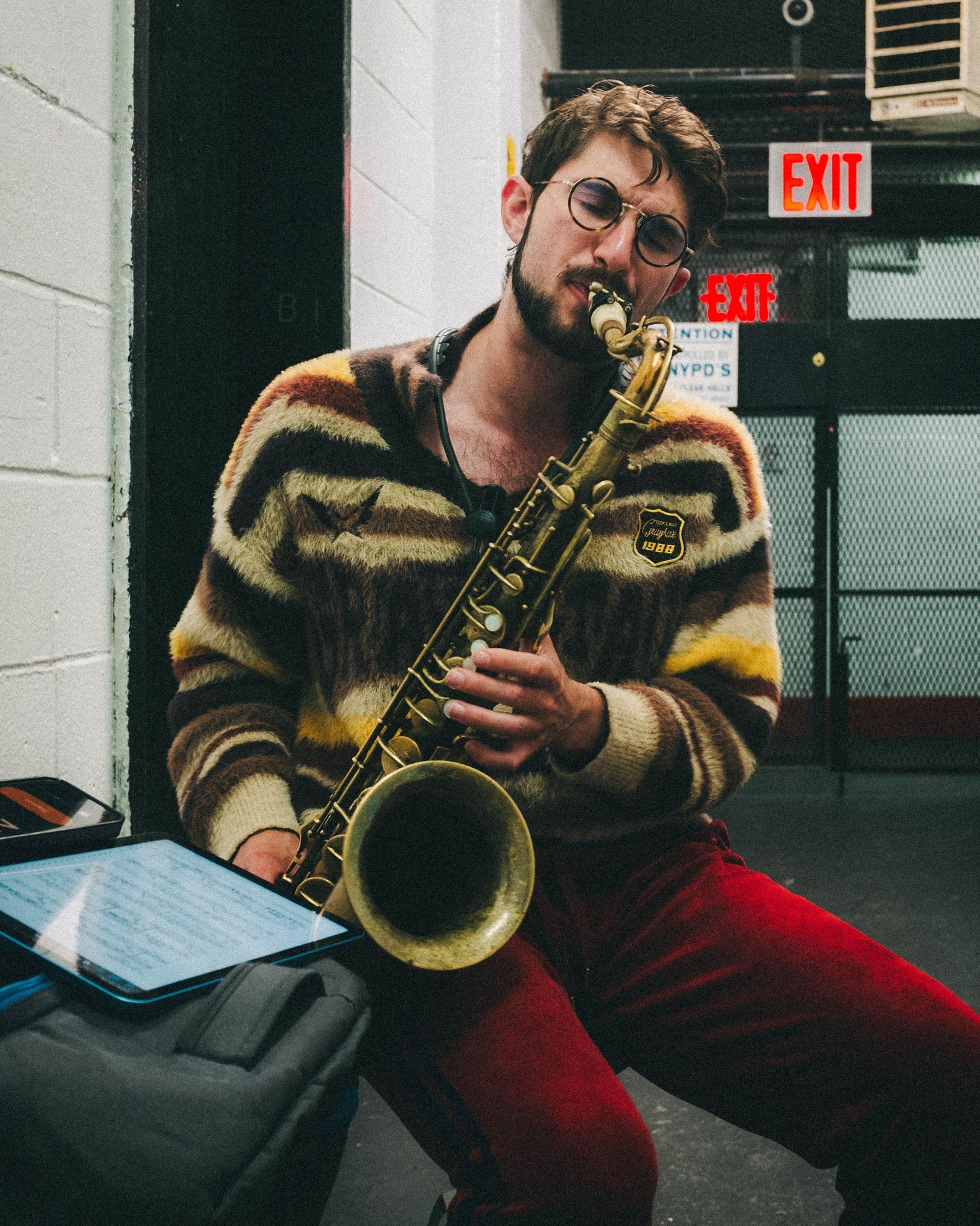 Man playing the saxophone in the basement of his Harlem apartment building
