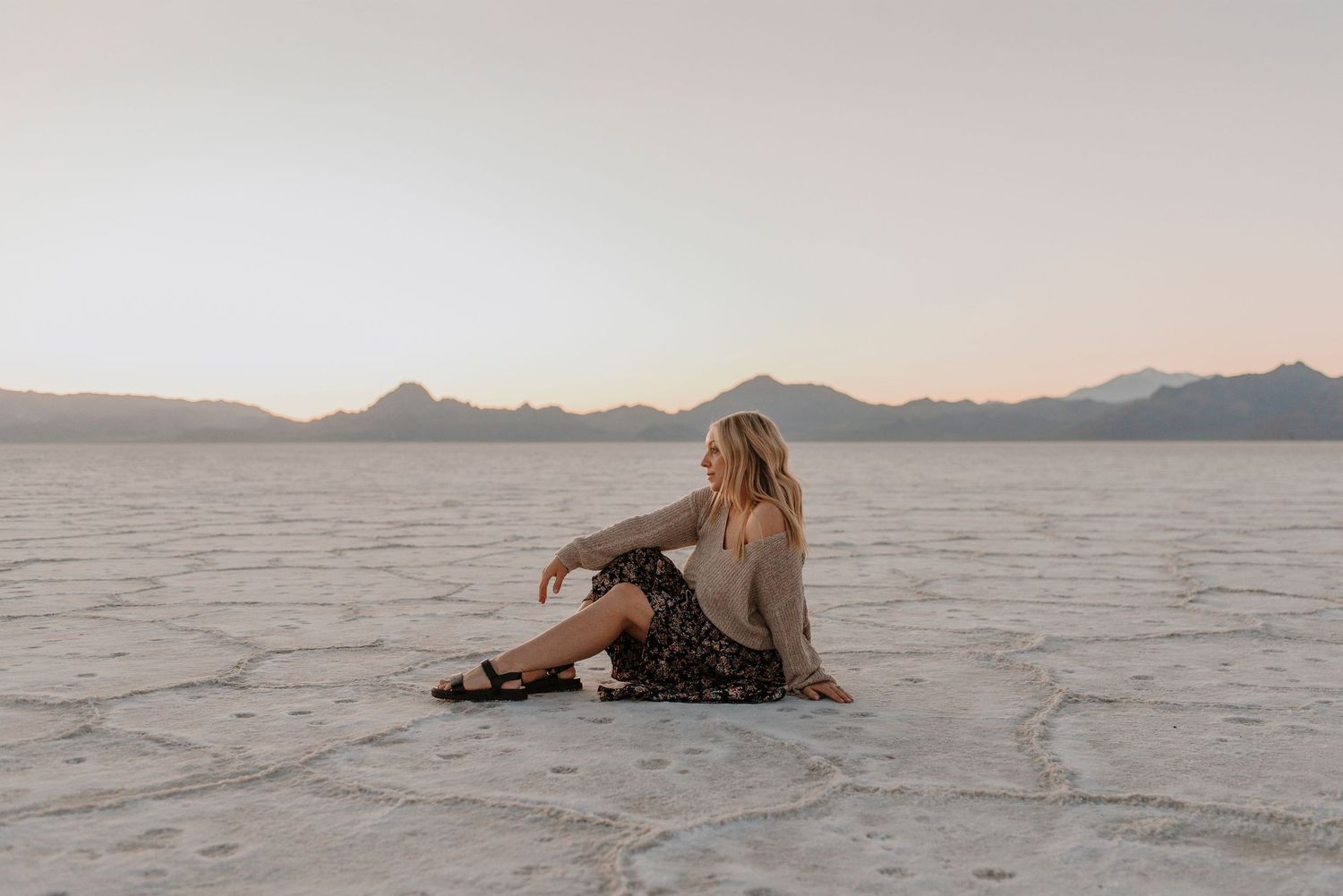 People walking across the expansive white salt flats with mountains visible in the distance.