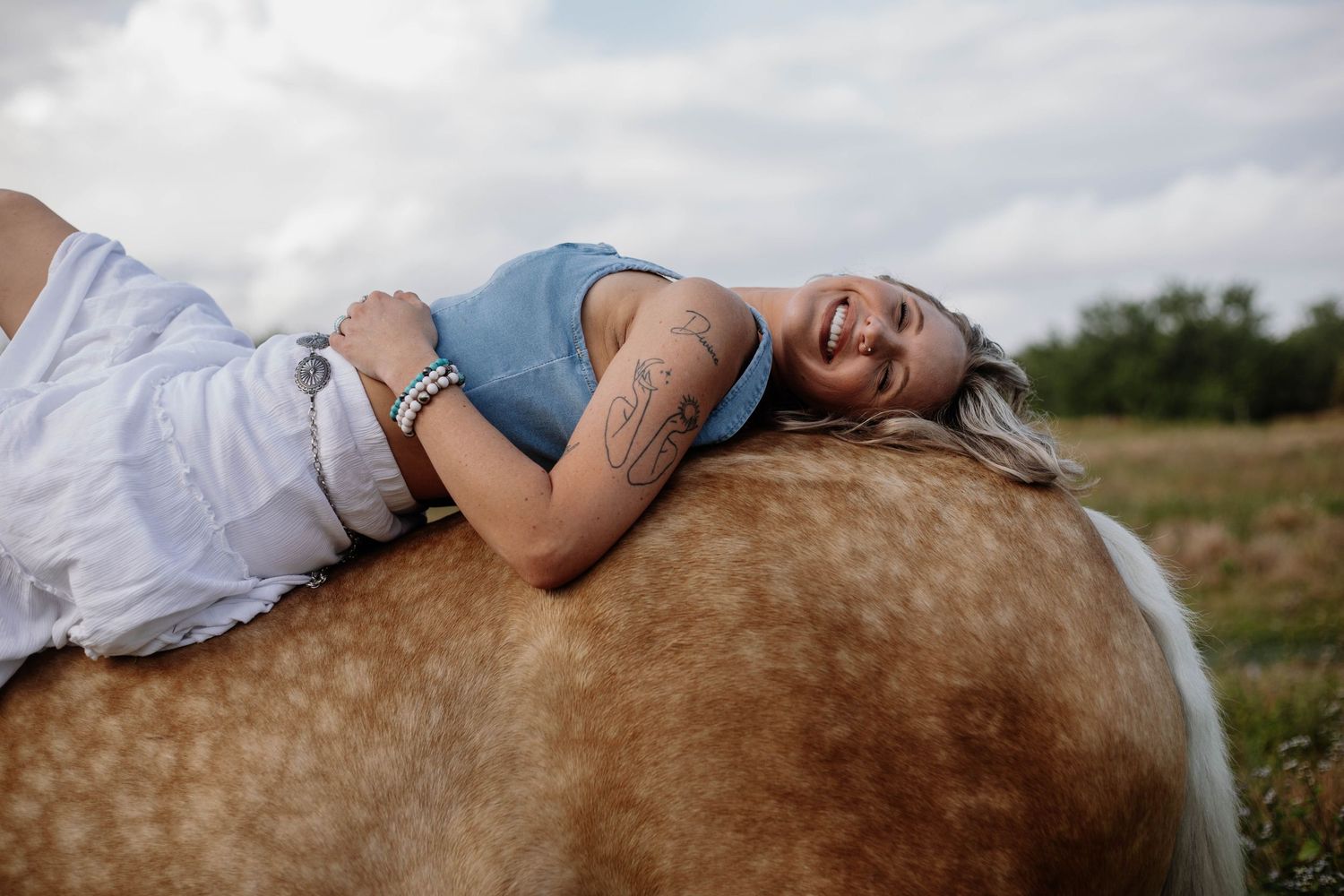 A couple lying together on a horse in a romantic outdoor photoshoot.