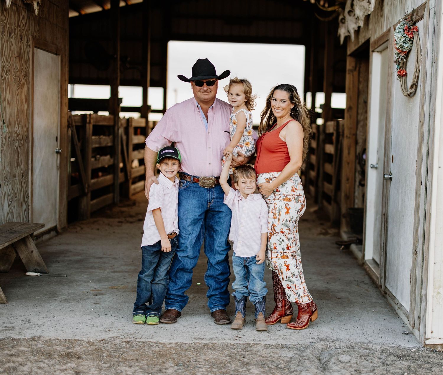 Family photoshoot in a rustic barn setting with western attire.
