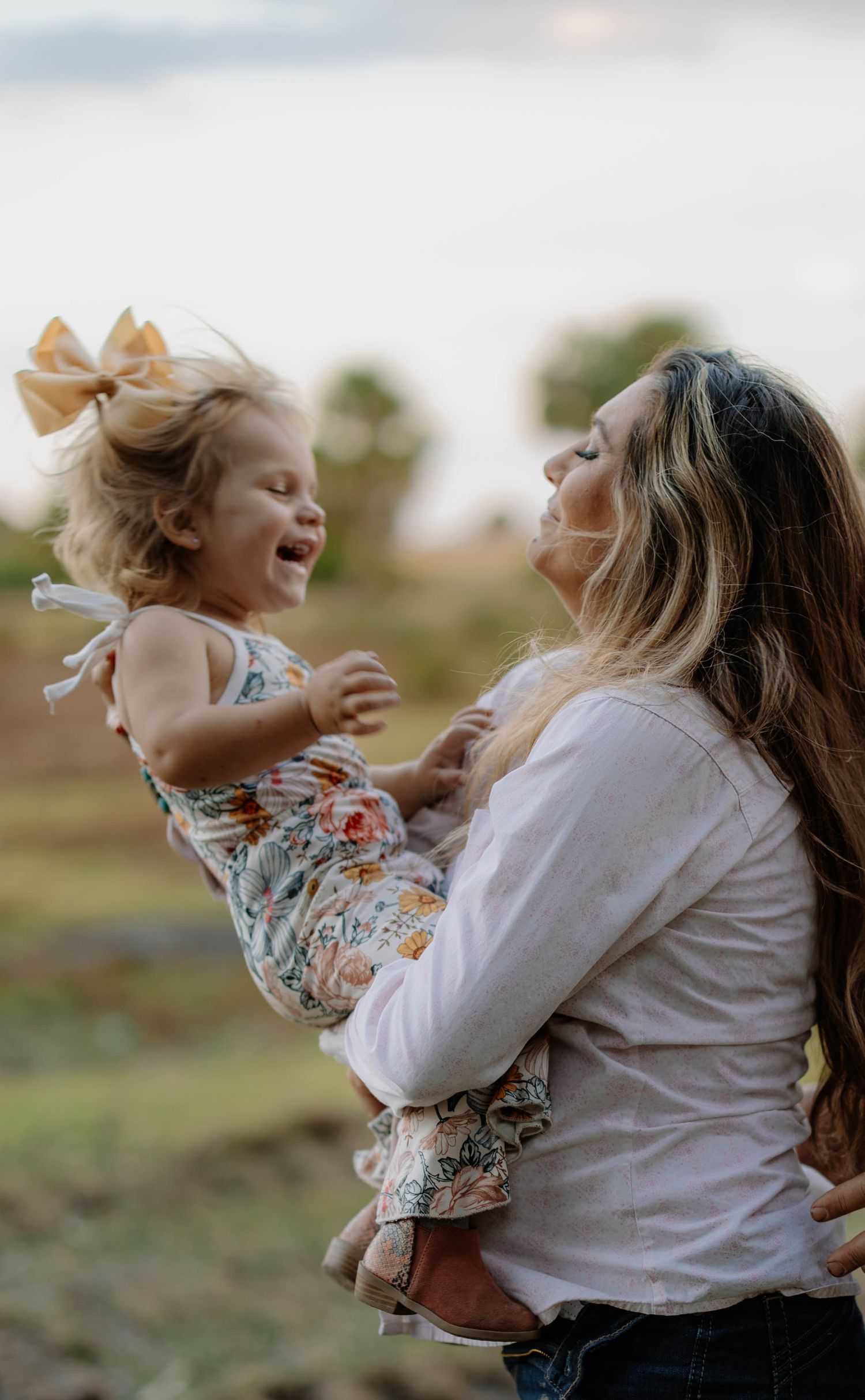 Joyful candid moment between parent and child playing outdoors in floral clothing.