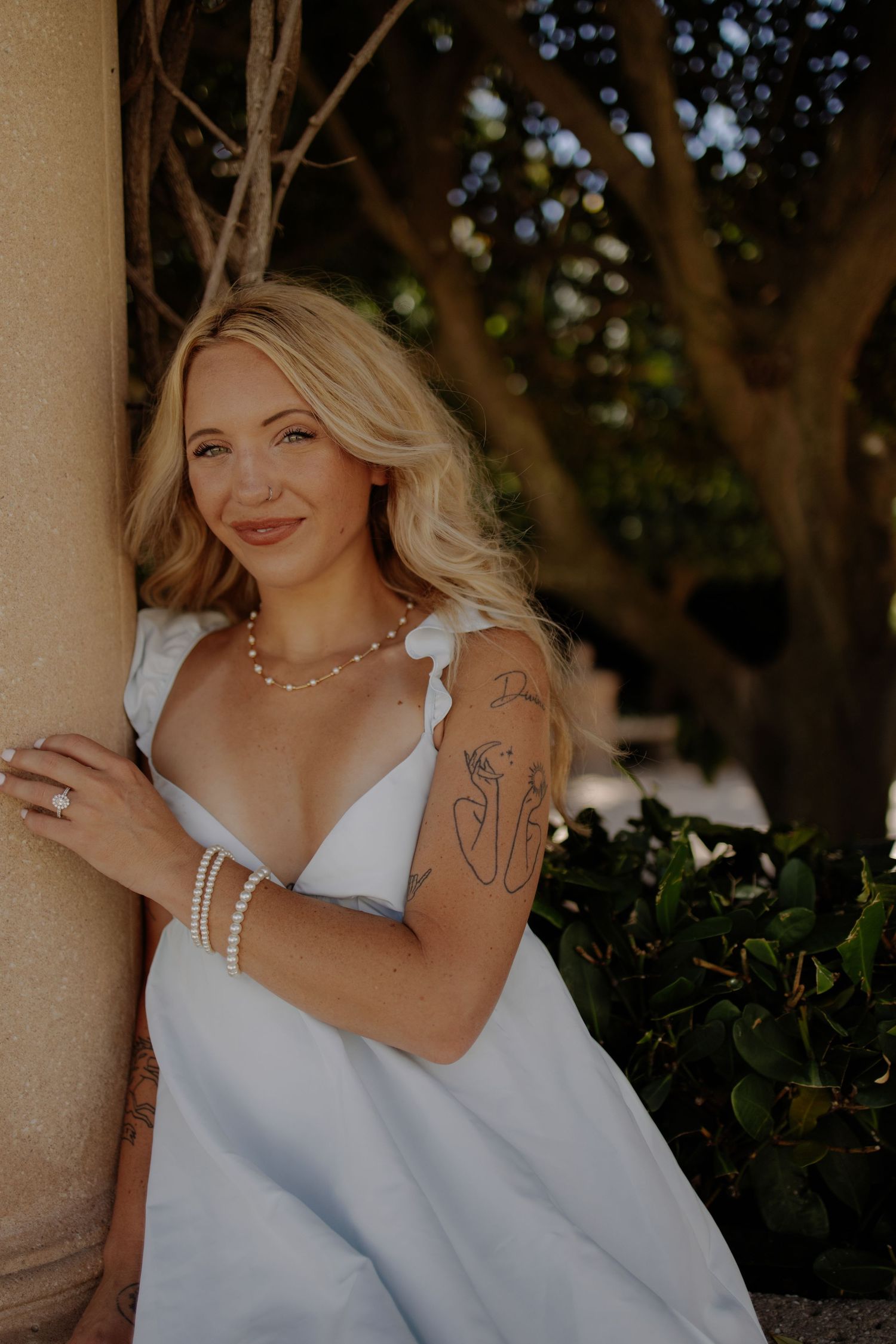 Person in white dress poses elegantly against a fountain backdrop.