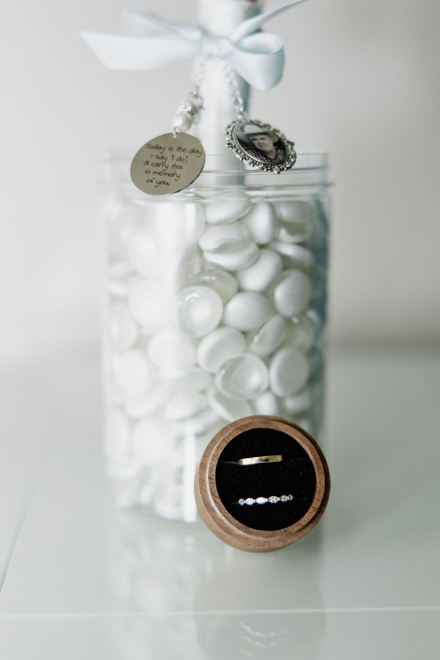 Delicate silver jewelry and white ribbons displayed in glass jars with elegant details.