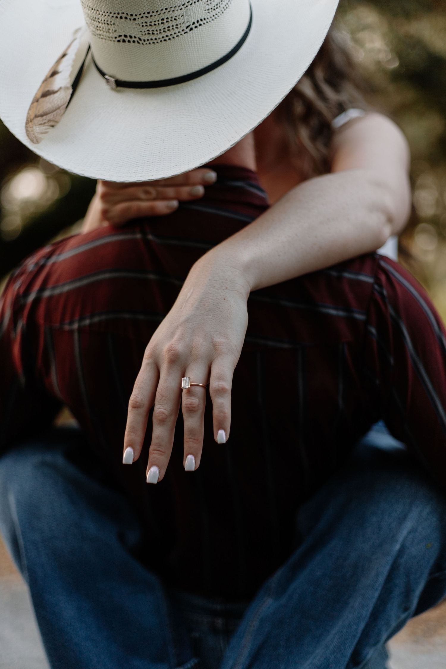 Close-up of hands showing wedding ring with white cowboy hat in frame.