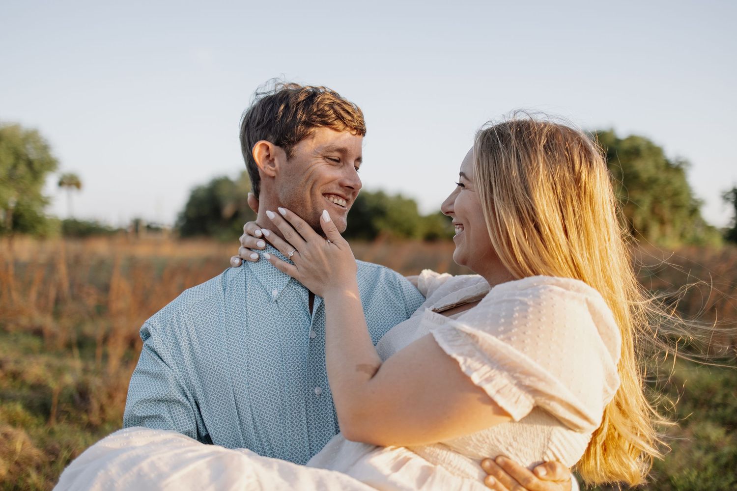 Couple embraces in golden sunlight during romantic outdoor photography session.