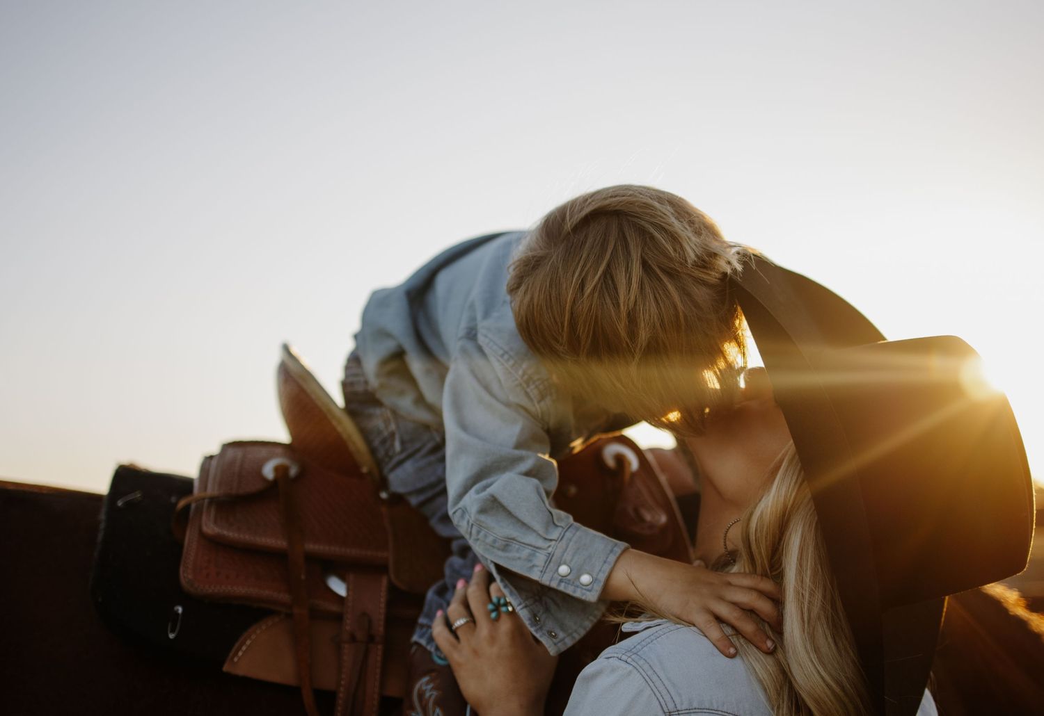 Couple embraces in romantic sunset silhouette against golden light.
