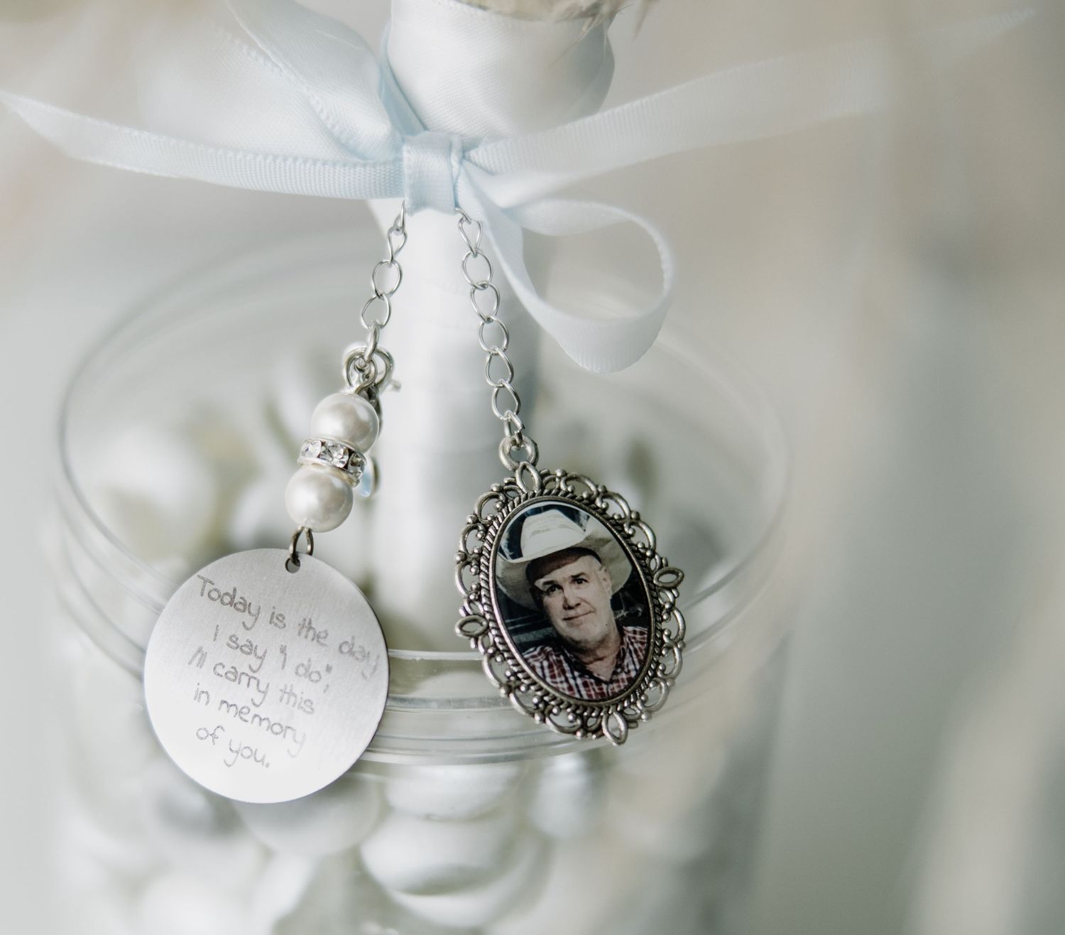Vintage-style silver necklaces and charms arranged with white ribbons in glass containers.