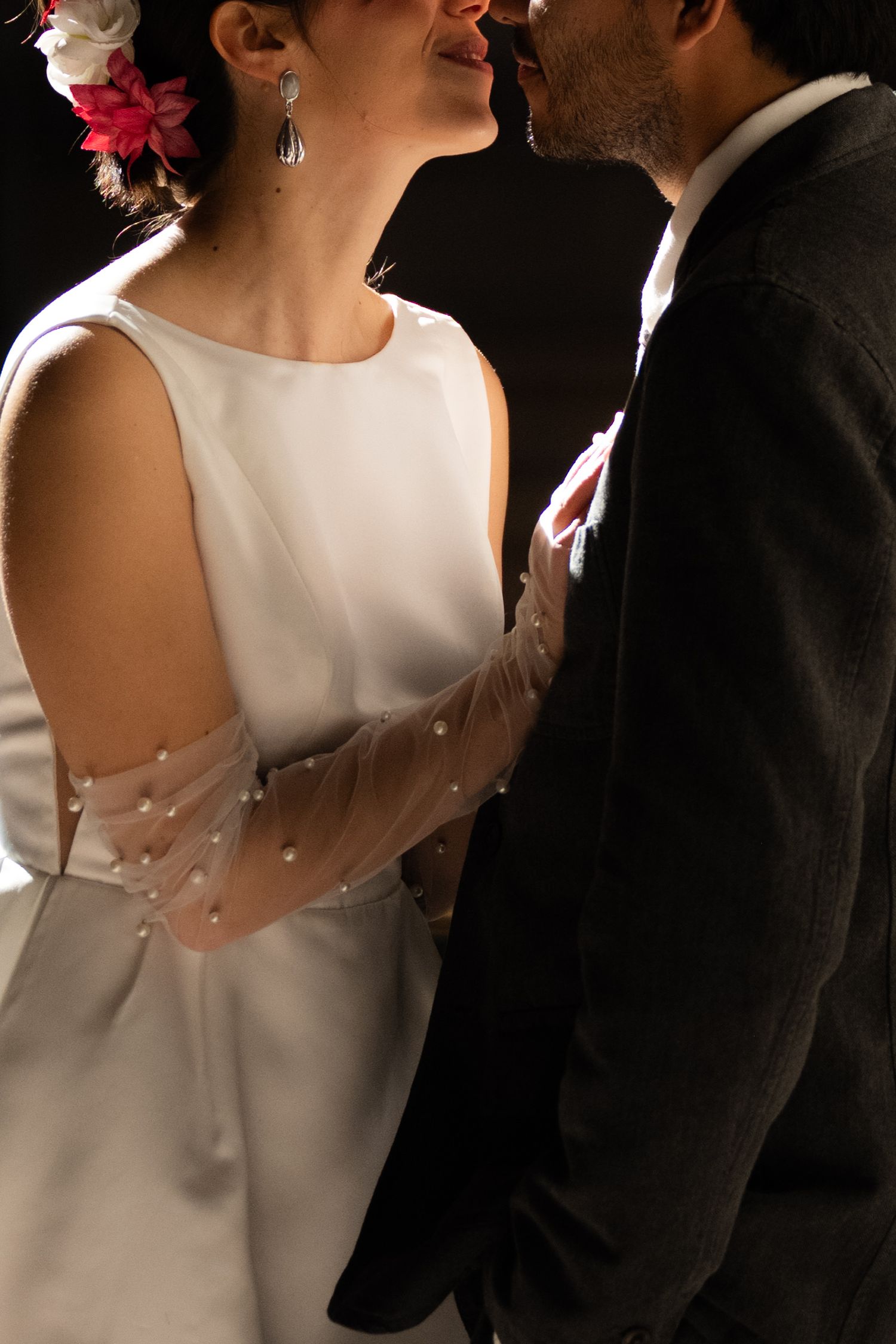 Bride in white dress with pearl tulle sleeves and groom share an intimate moment at wedding.