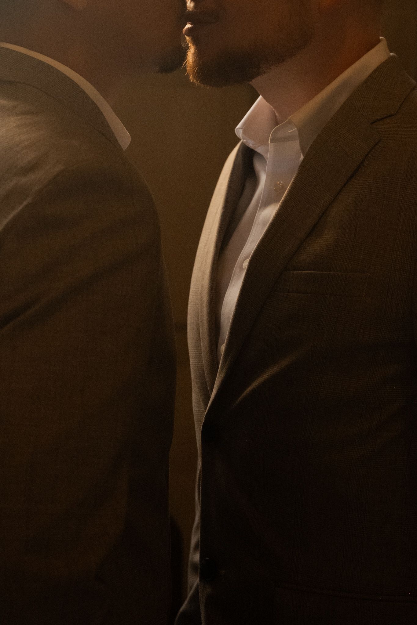 Close-up portrait of groom in gray suit and tie at an intimate same-sex wedding ceremony.