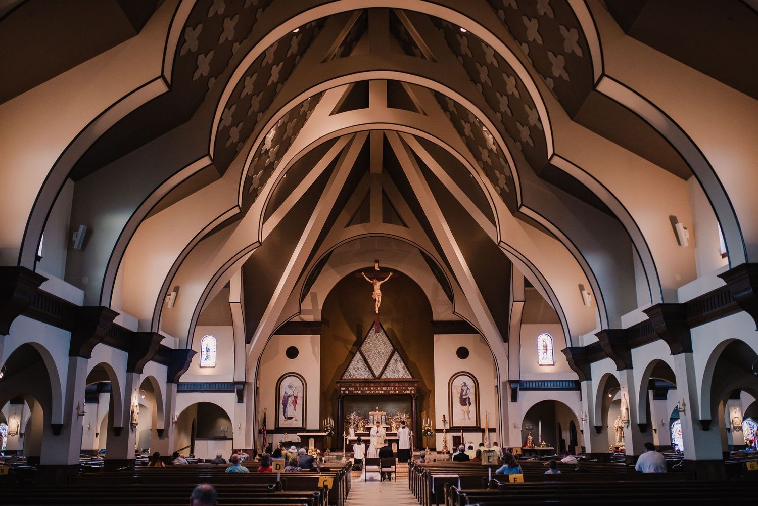 A panoramic view of an elegant church interior with vaulted ceilings and gothic arches in warm lighting.