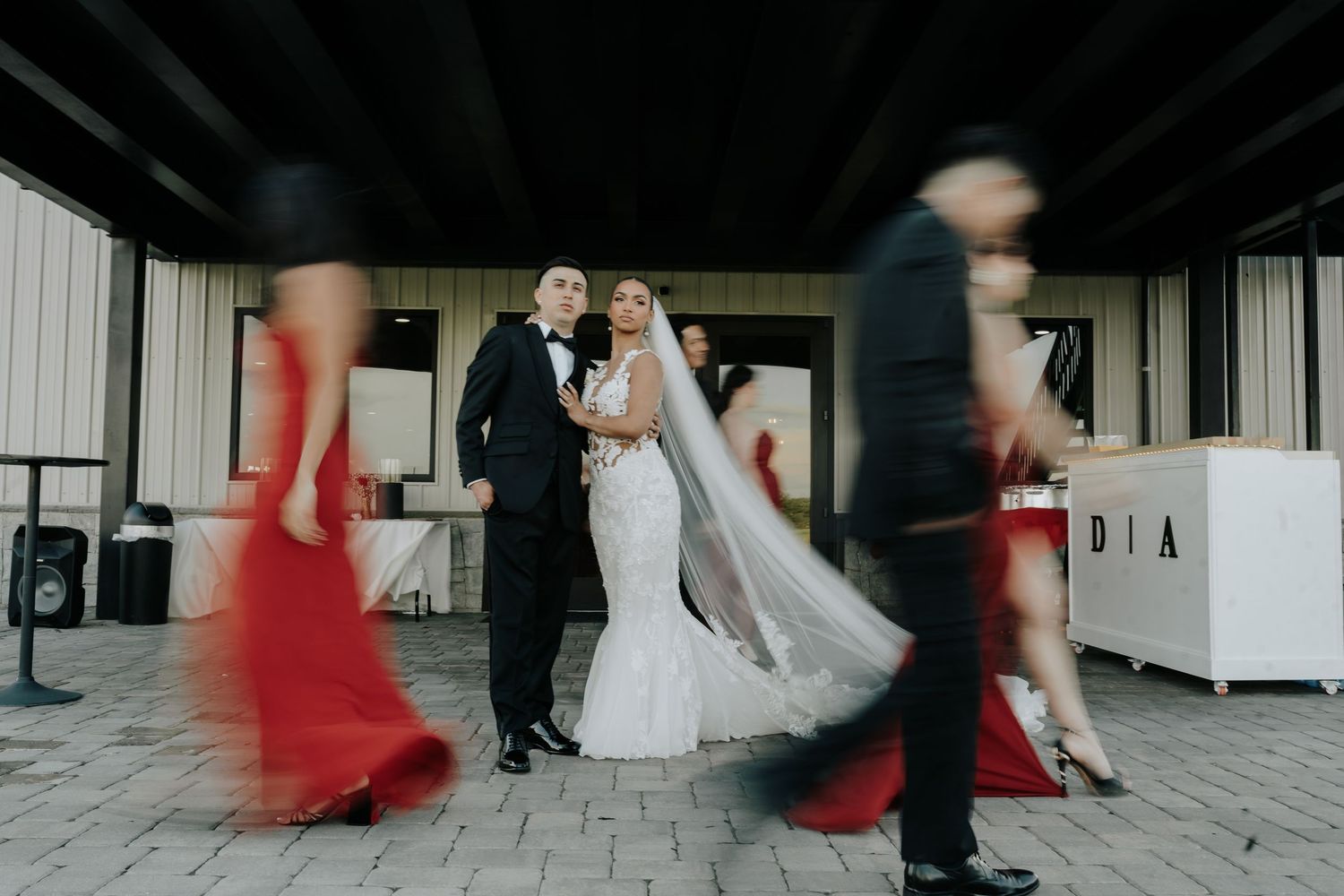Wedding party in red dresses and formal attire twirl across a dance floor at an elegant wedding.