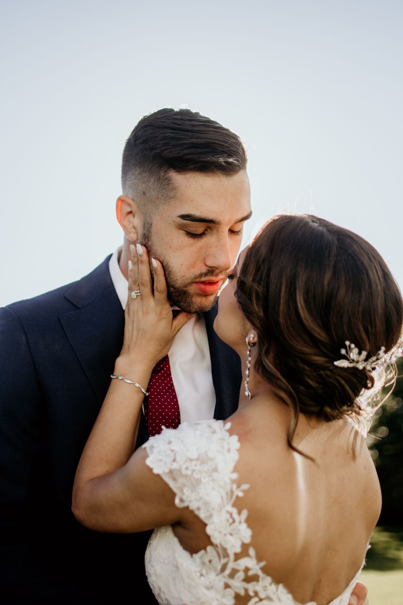 Romantic wedding photo shows tender moment between newlyweds with bride in lace dress and groom in navy suit at sweeney barn Manassas