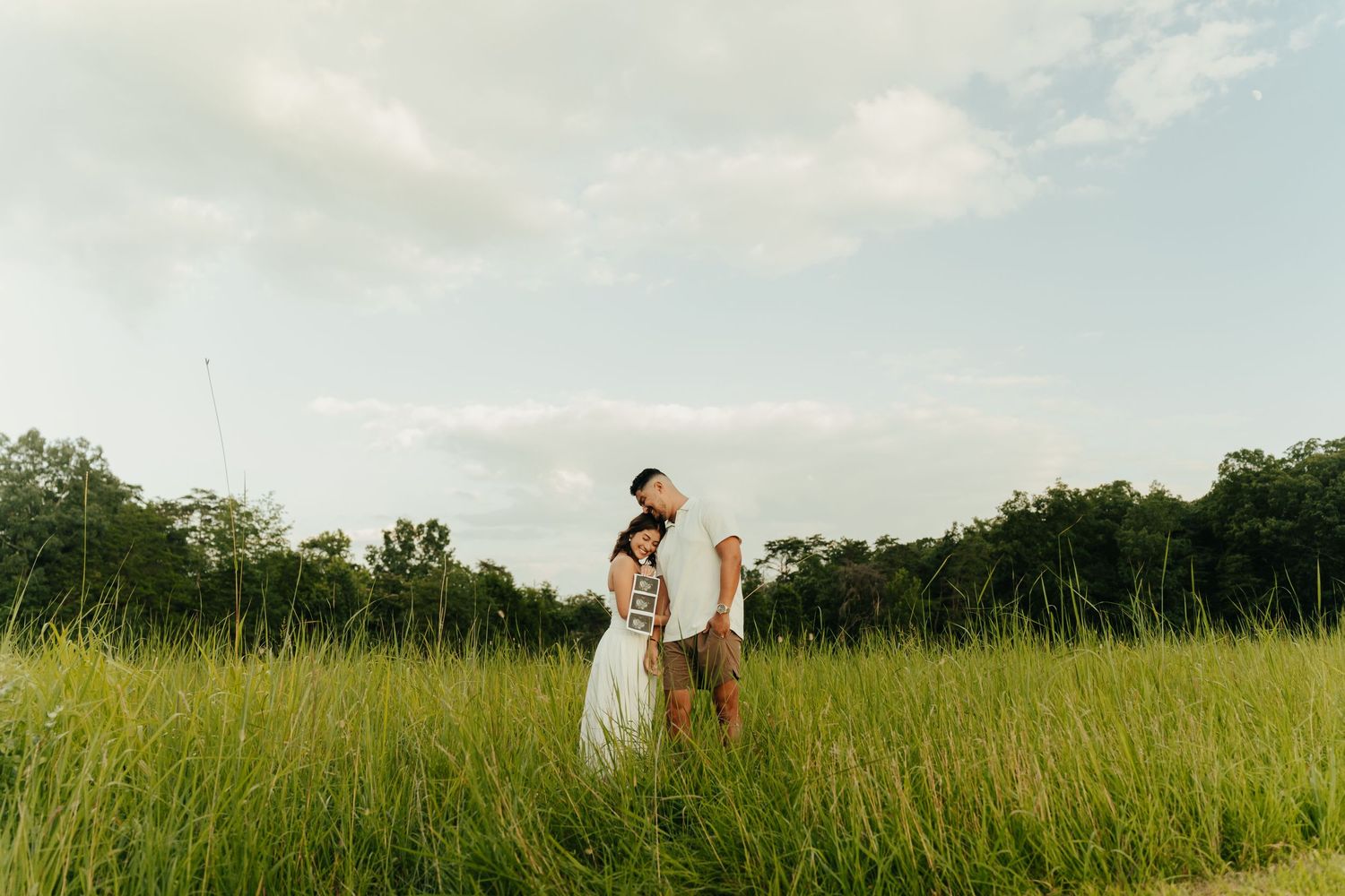 Couple walking through a serene golden meadow at sunset with tall grass swaying in the breeze.