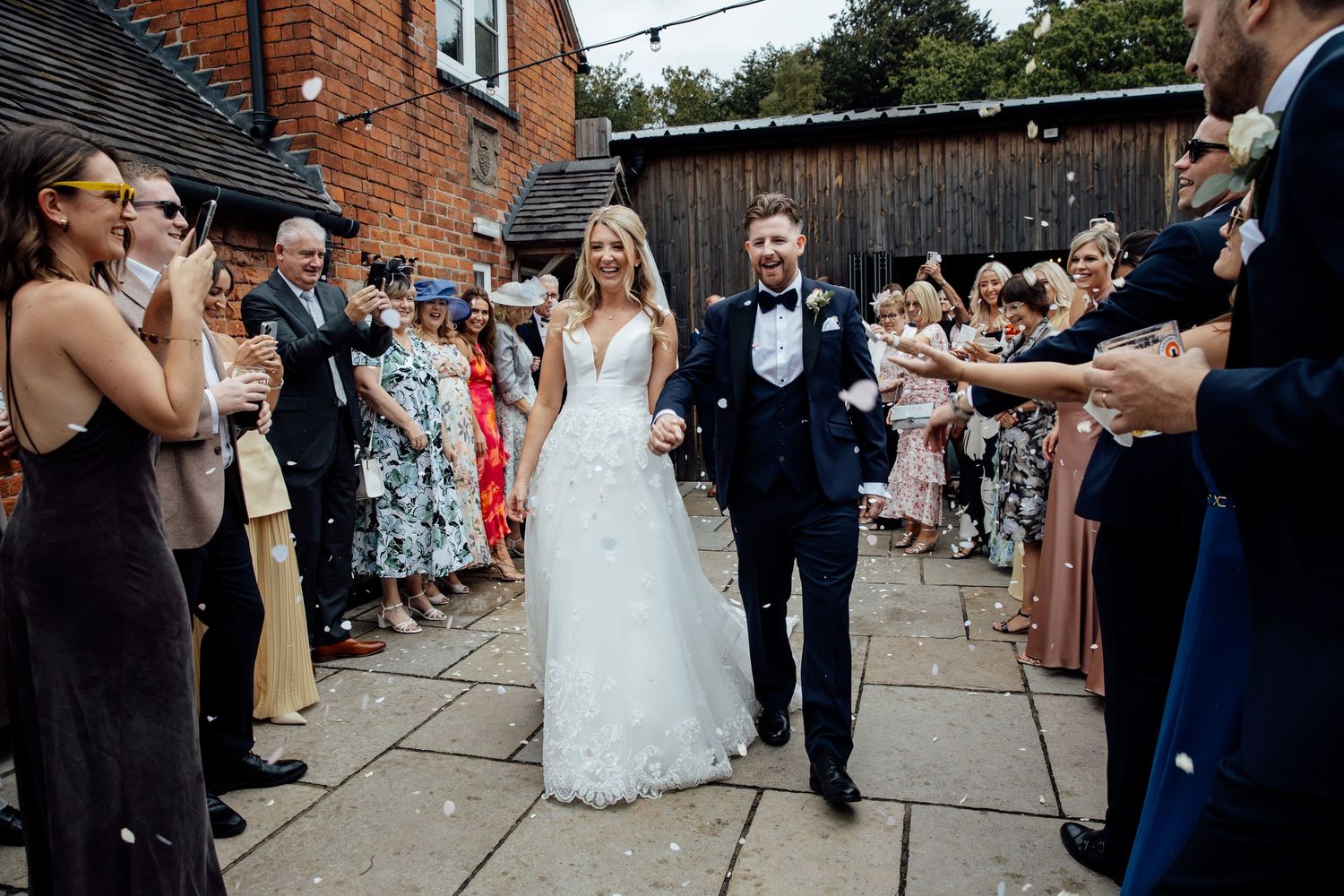 Wedding procession walks through guest-lined pathway at outdoor venue.