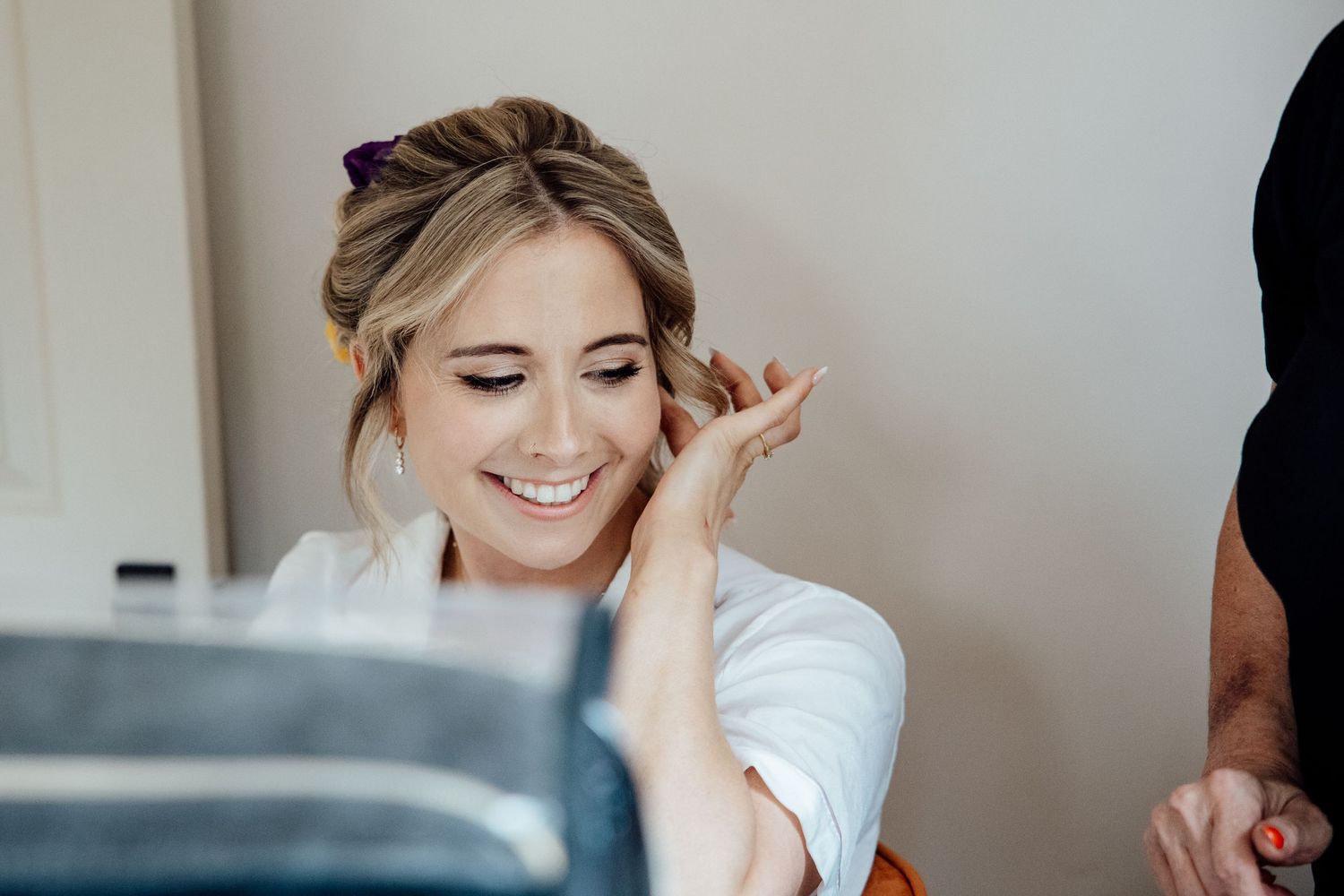 A bride getting ready on her wedding day with a joyful expression.