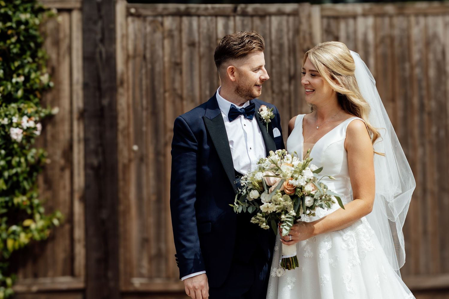 Wedding couple shares intimate moments against a rustic wooden fence backdrop.