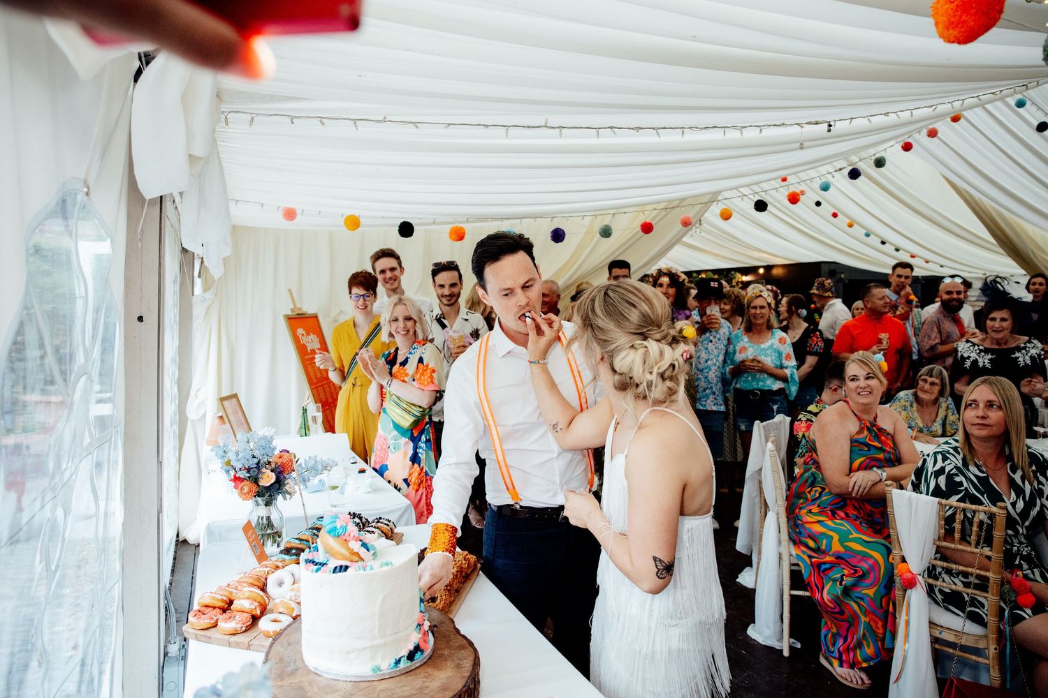 Wedding reception tent decorated with white draping and colorful bunting.