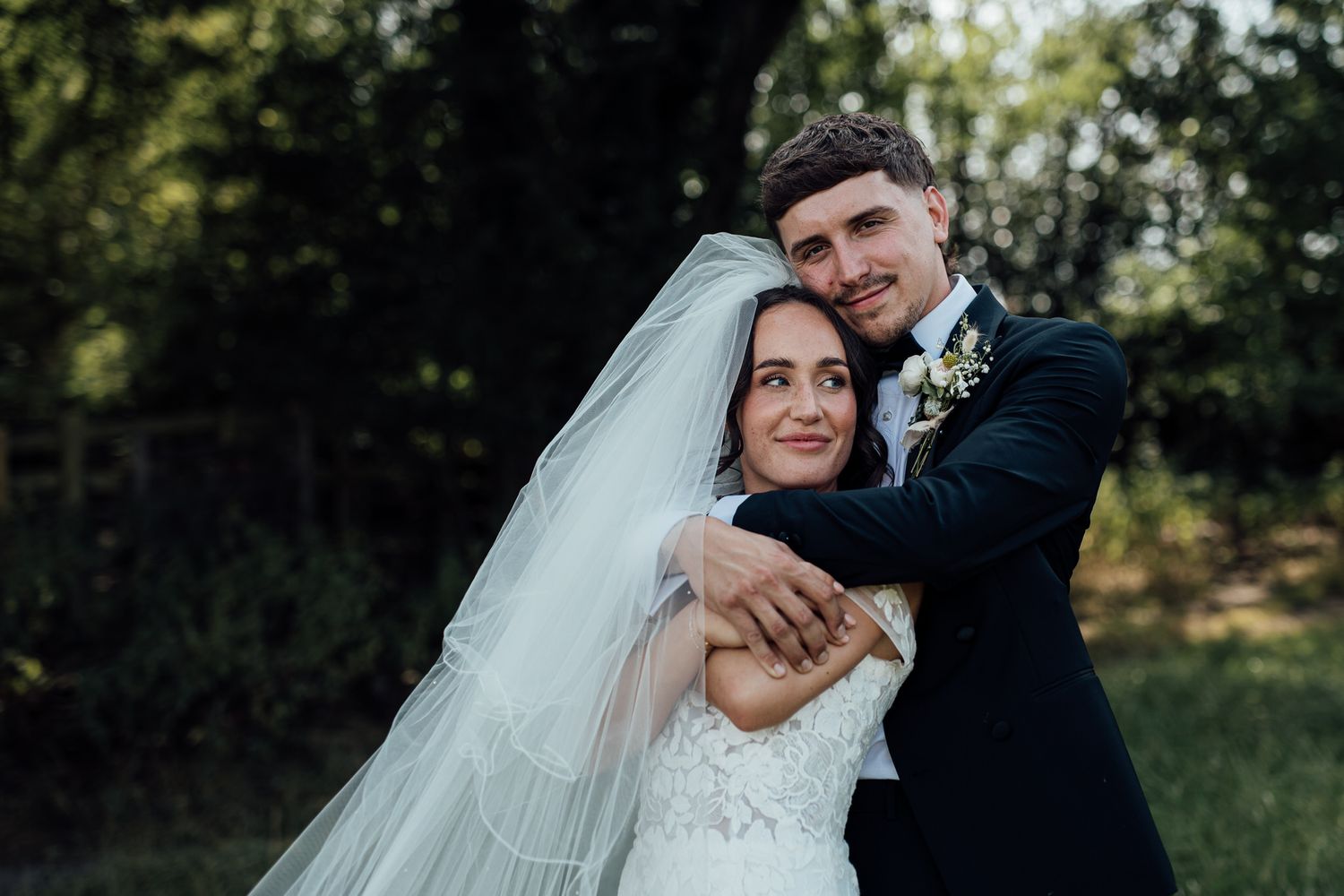 Romantic outdoor wedding portraits with couple embracing in natural garden setting.