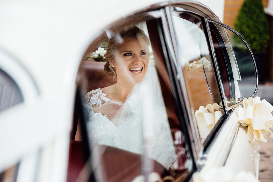 Close-up view through car window of bride in wedding dress.