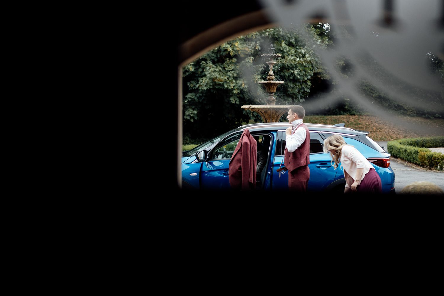 Silhouettes of parked cars seen through a rainy window.