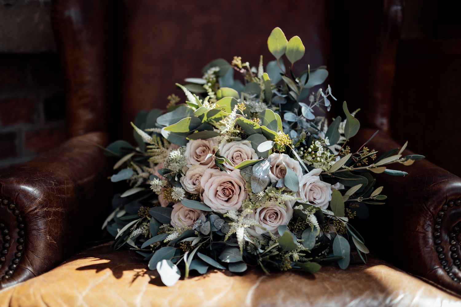 Elegant floral arrangements with roses and eucalyptus leaves on display.