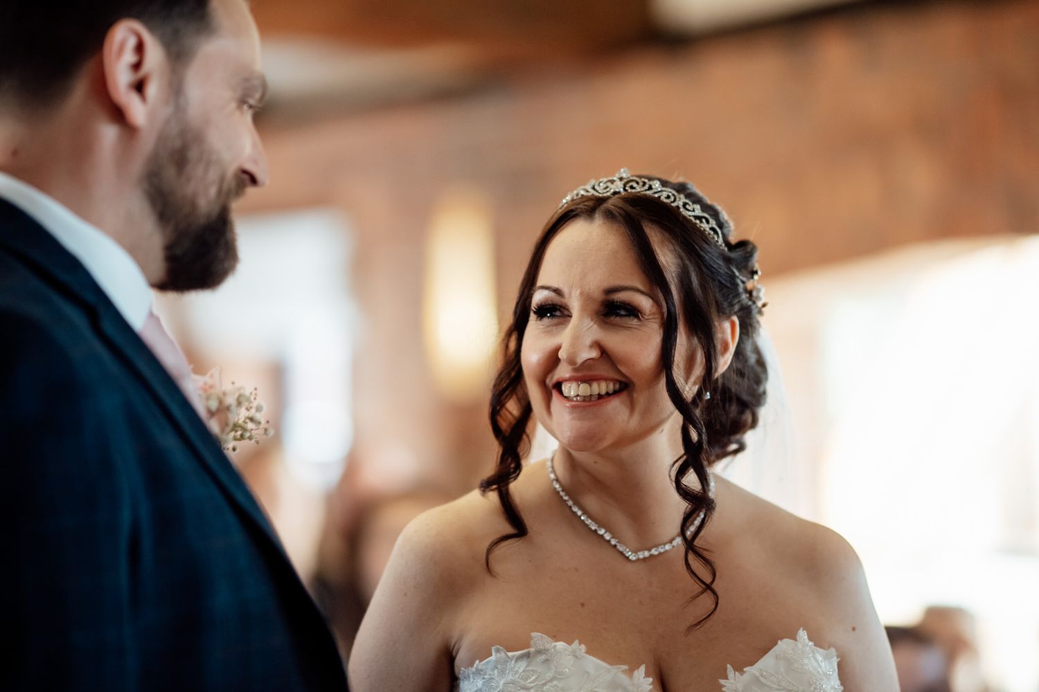 A joyful wedding celebration moment with guests laughing and embracing in a rustic venue.