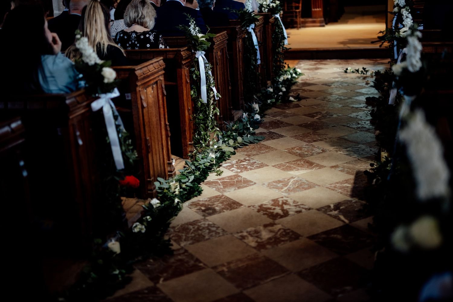 Candlelit wedding aisle decorated with greenery and romantic evening ambiance.