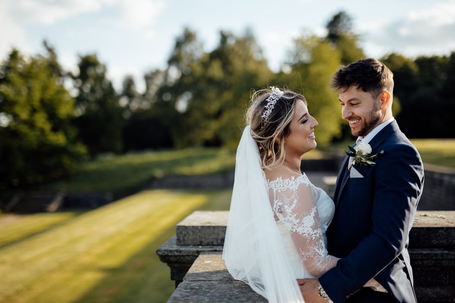 Romantic outdoor wedding portraits captured during golden hour with dramatic lighting and flowing veil.