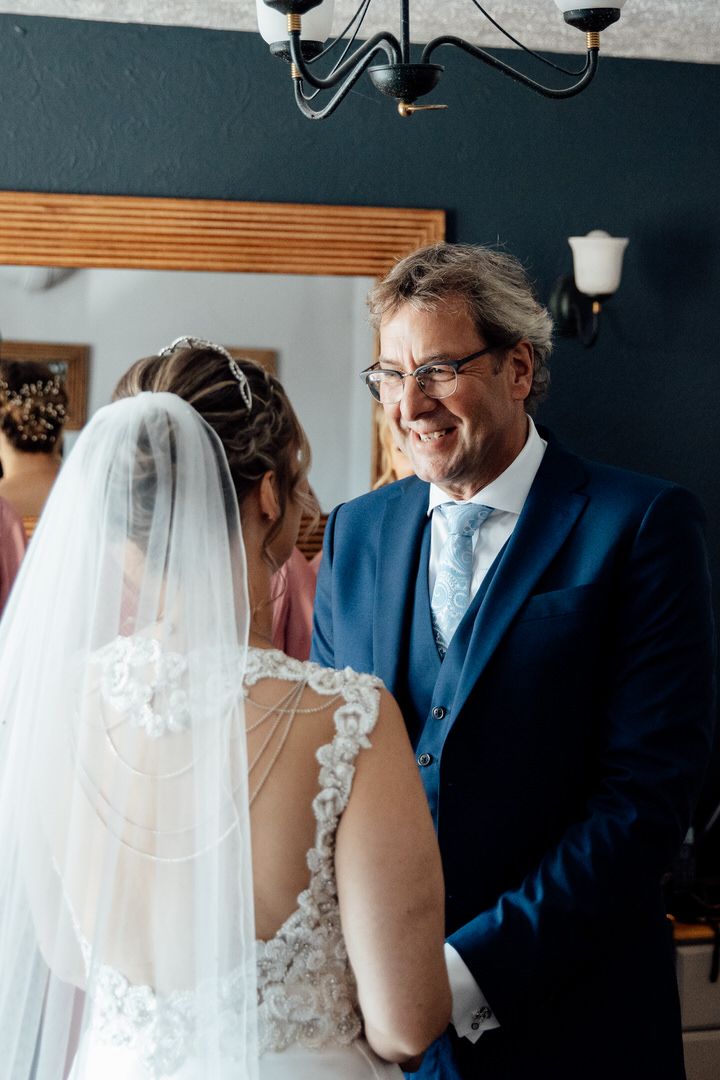 Wedding couple sharing an intimate moment against a dark blue wall with wooden accents.