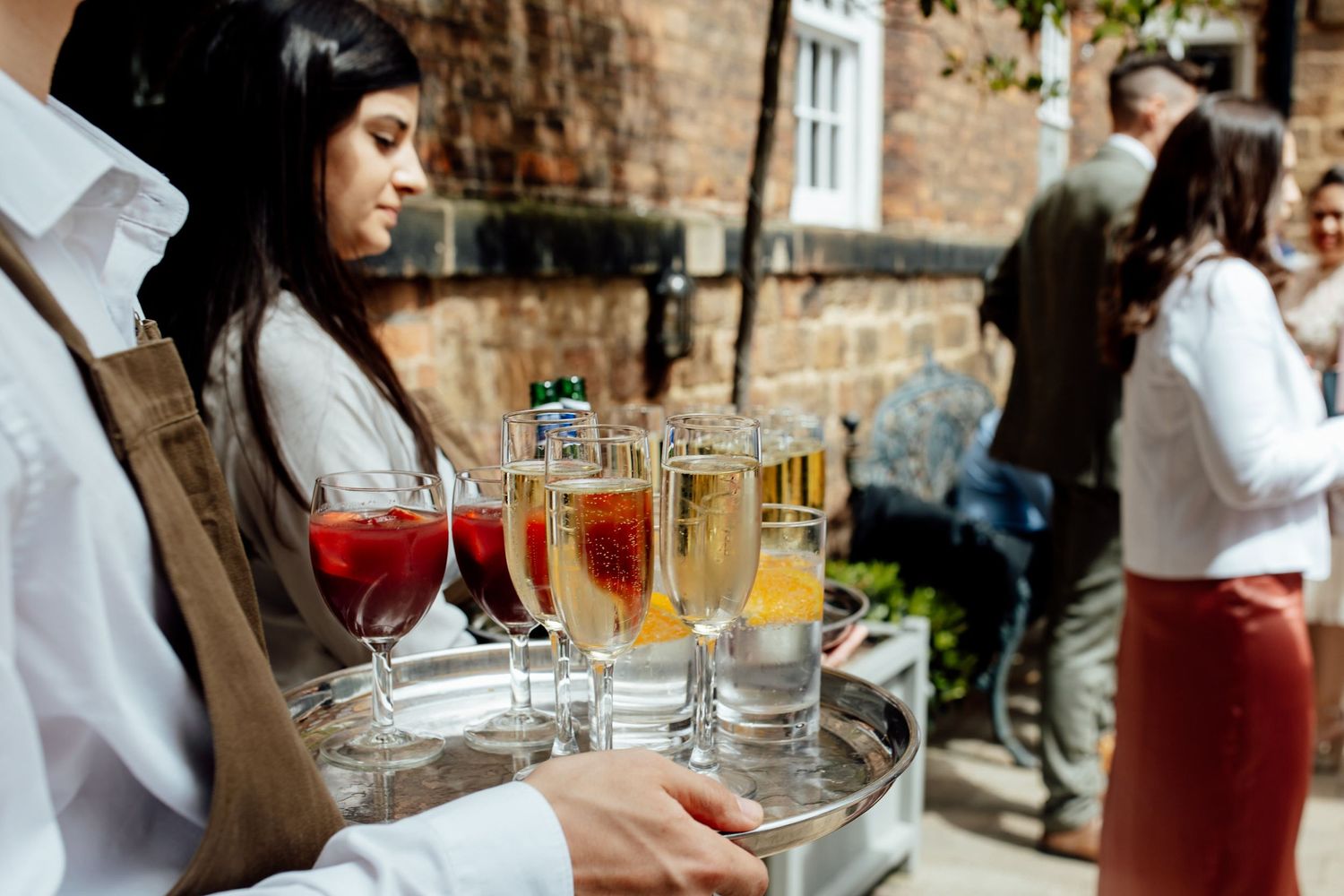 Elegant cocktail service with various drinks arranged on wooden surfaces in natural light.