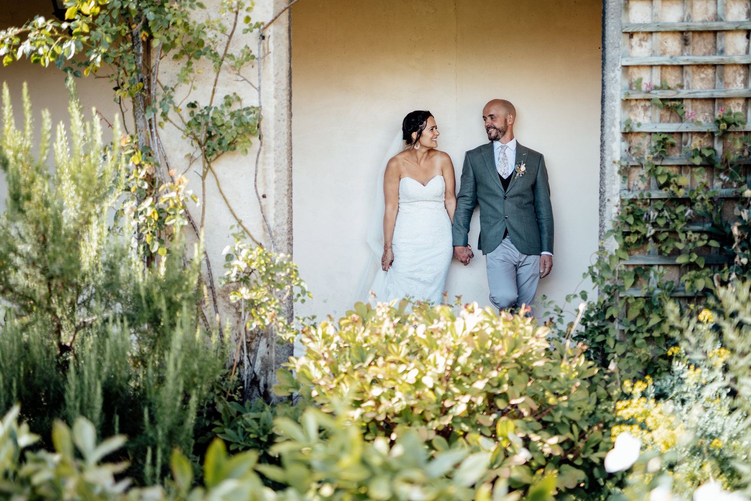 Wedding couple poses in a garden walkway with Mediterranean architectural elements.