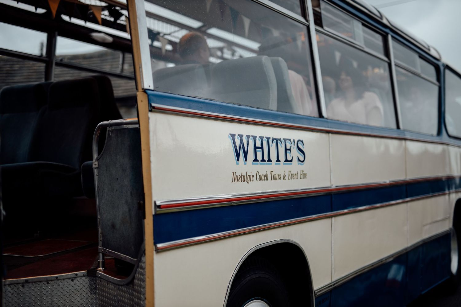 Vintage White's coach bus with blue stripe detail shown from side angle.