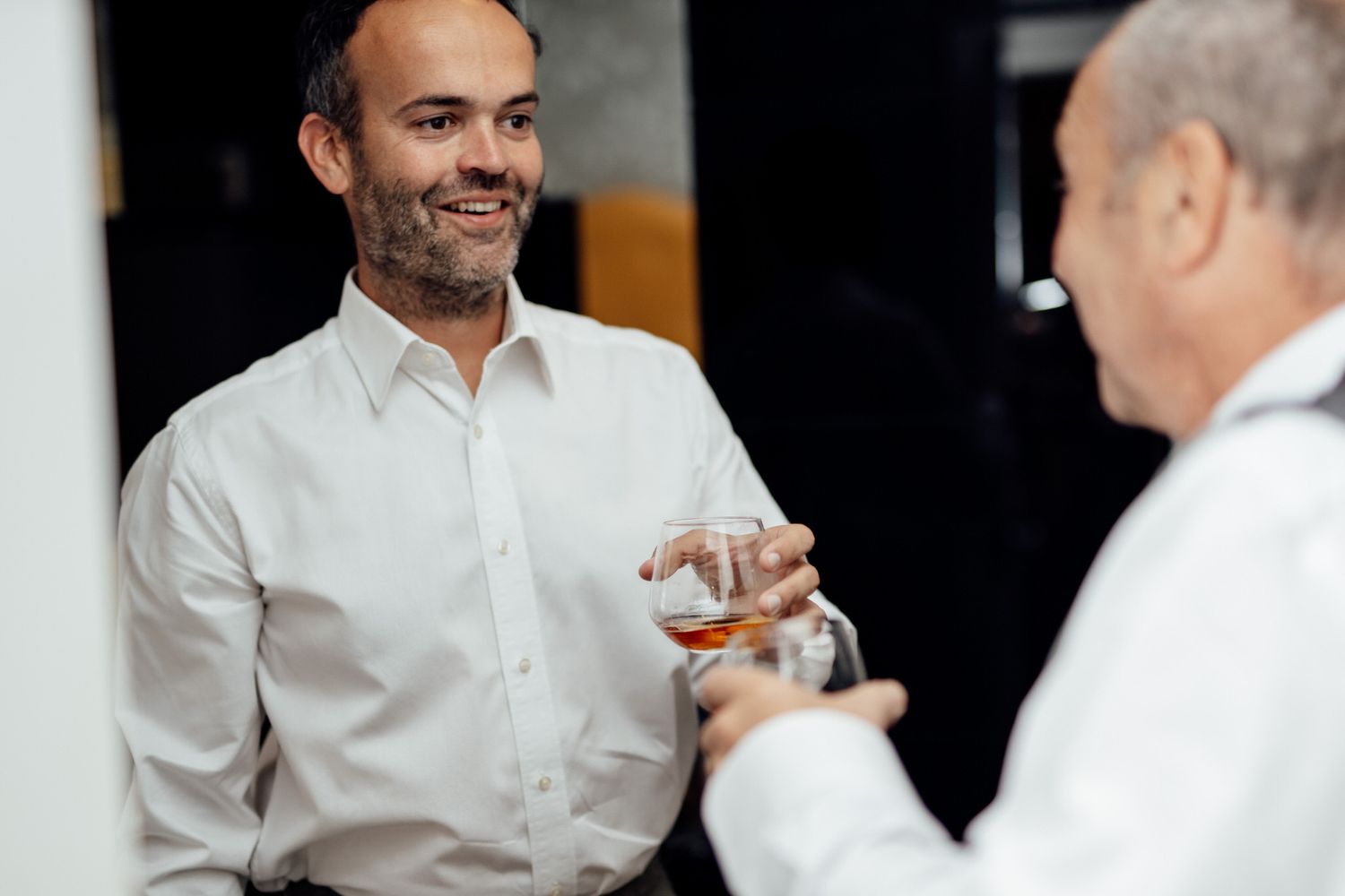 Wedding reception guests in white shirts socializing at formal event.
