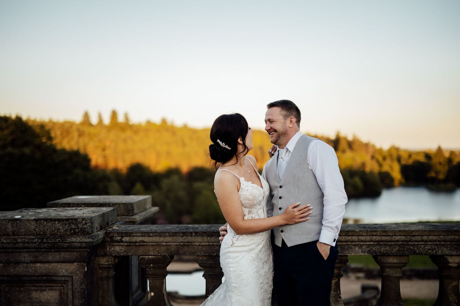 Couple shares intimate sunset moment on stone terrace overlooking scenic lake view.