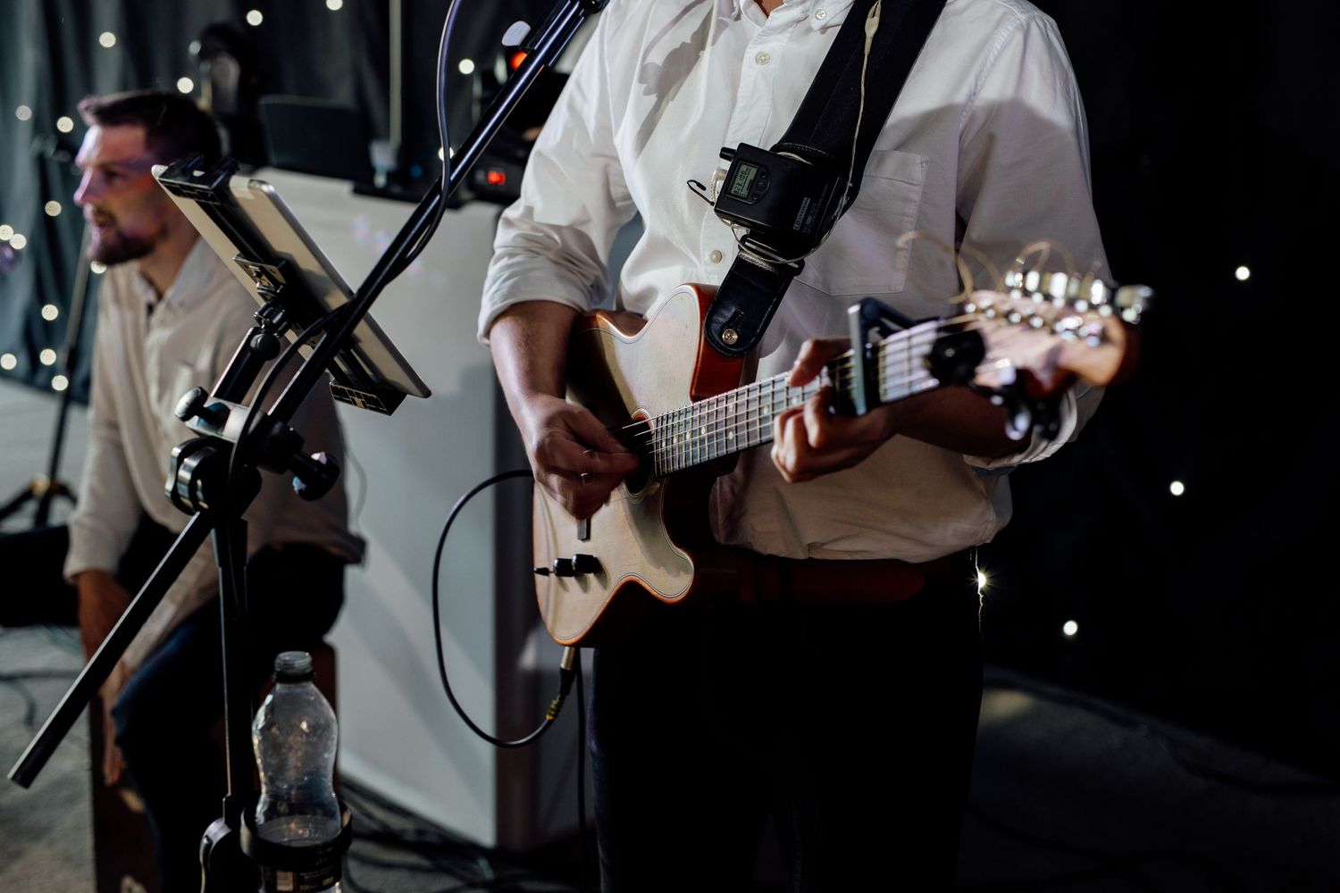 Close-up of a musician playing guitar during a wedding reception performance.