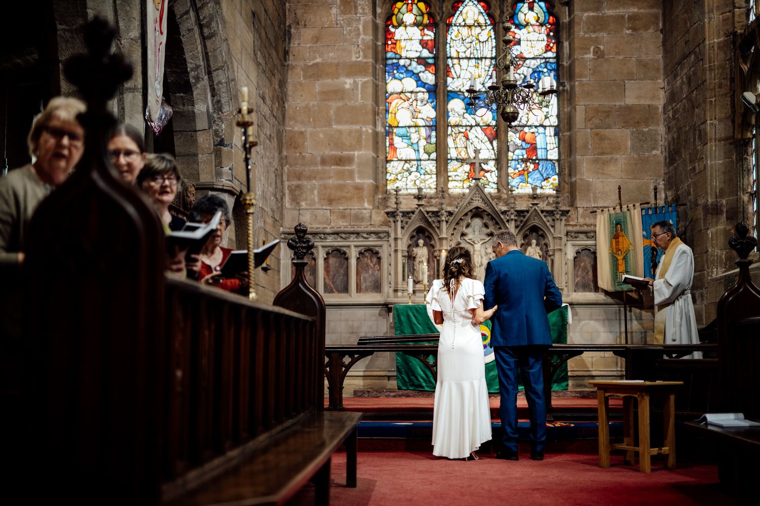 Interior of a historic church with stained glass windows during a wedding ceremony.