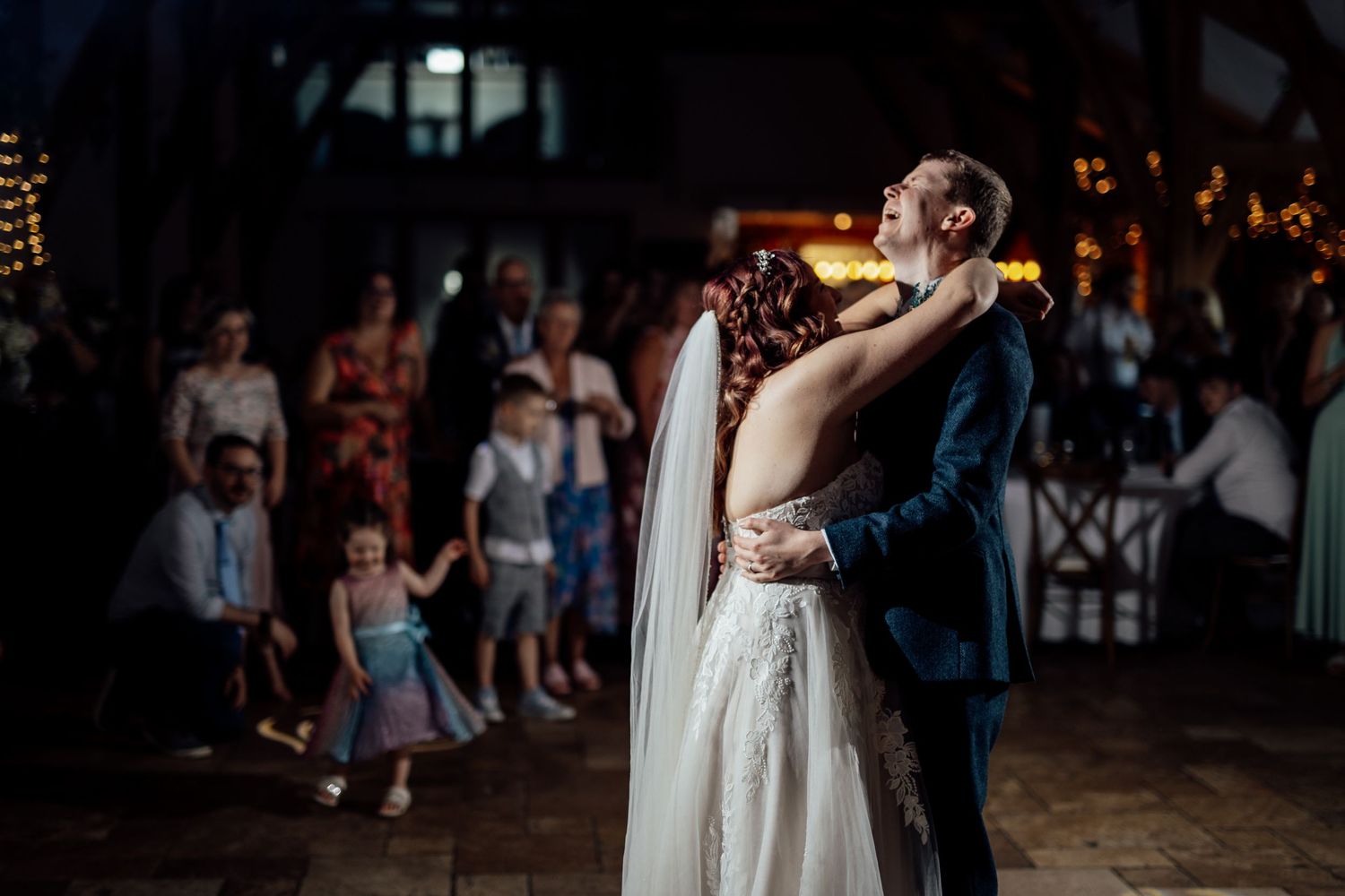 First dance at wedding reception with guests watching in background.