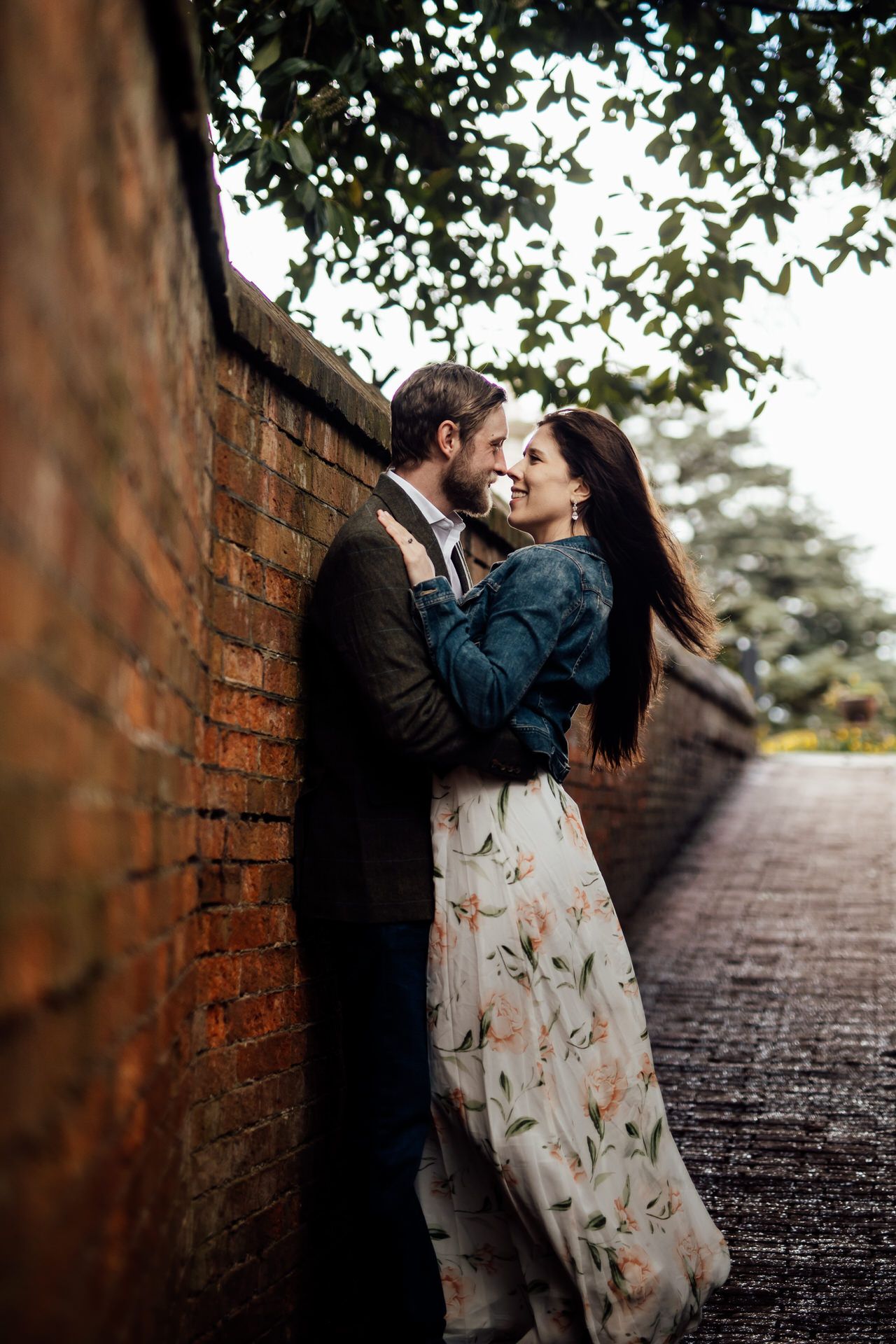 Couple sharing romantic moment against rustic brick wall.